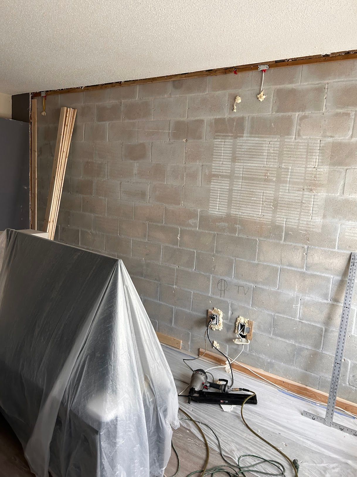 A room with a brick wall and a couch covered in plastic.