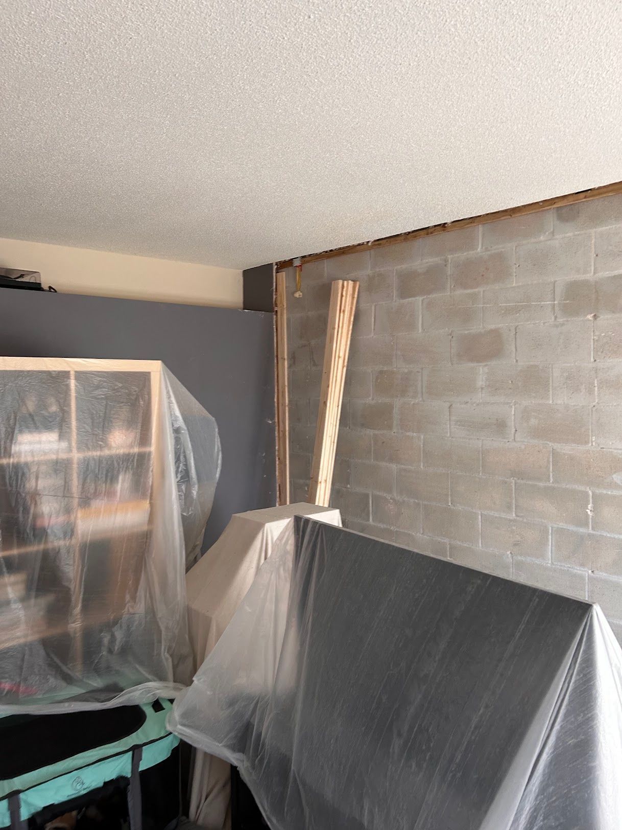 A room with a couch covered in plastic and a brick wall