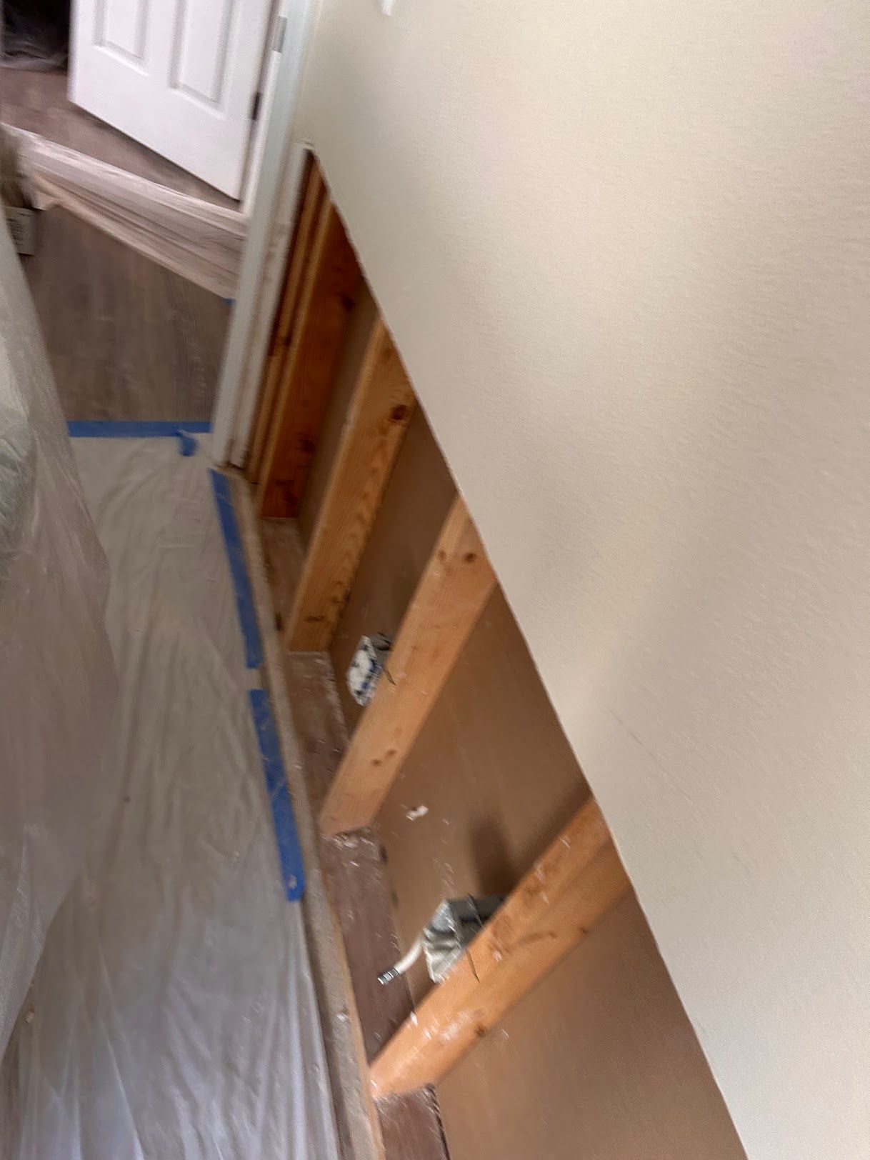 A room with a hole in the wall and wooden beams.