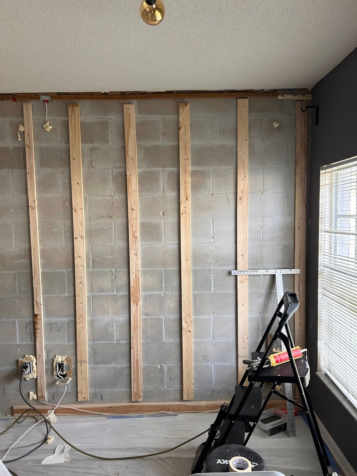 A room with a ladder in front of a brick wall.