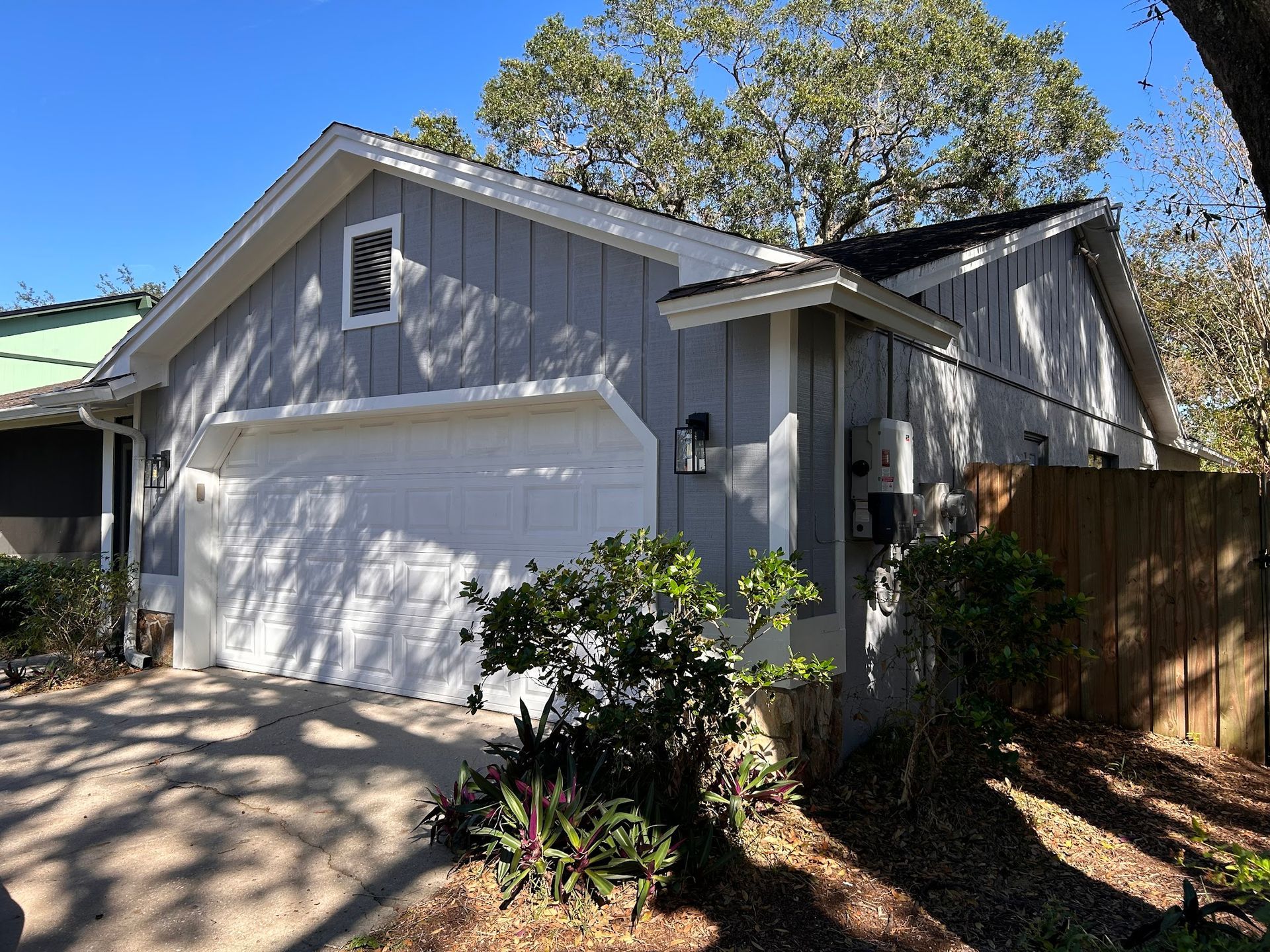 A house with a white garage door and a fence in front of it.