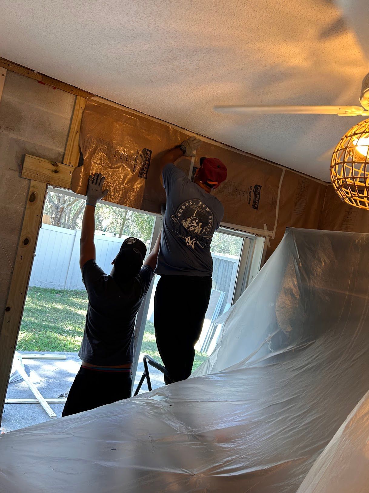 Two people are working on a window in a room.