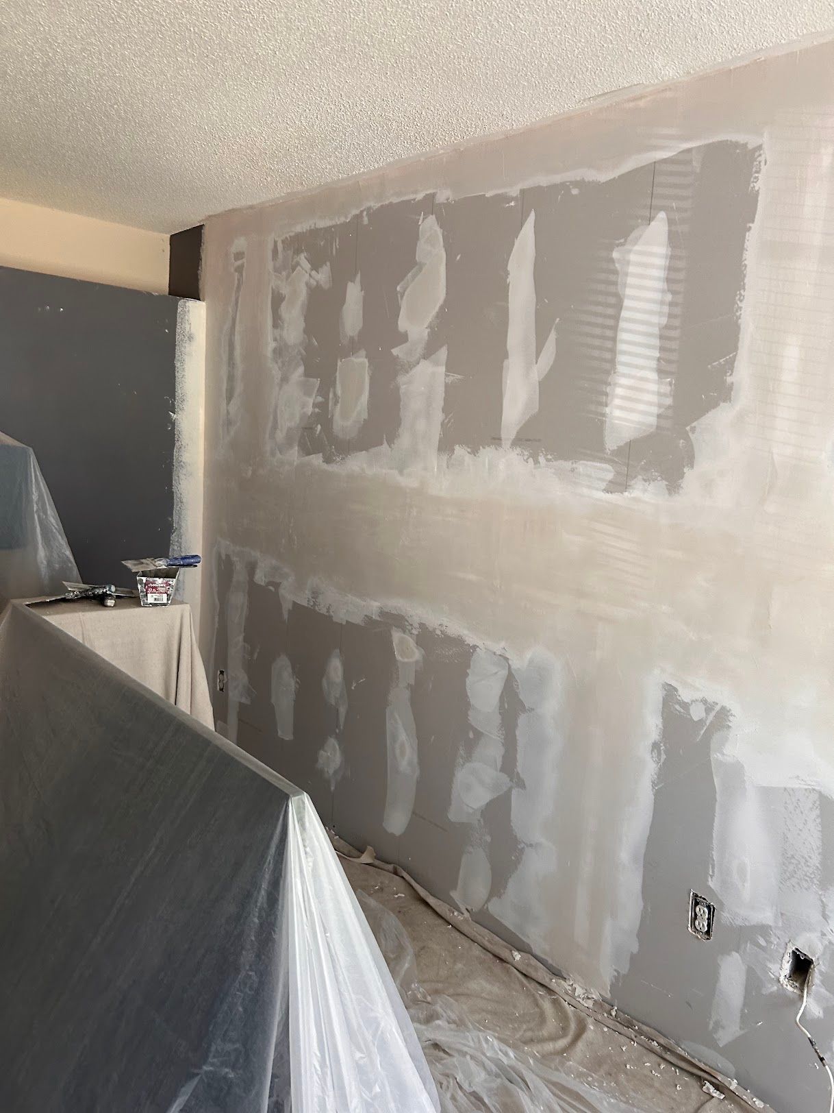 A room with a wall that is being plastered.