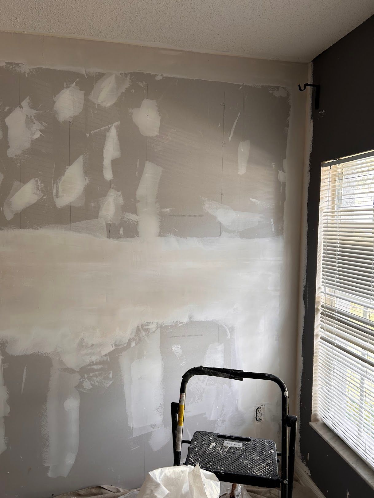 A room with a ladder and a window with blinds.