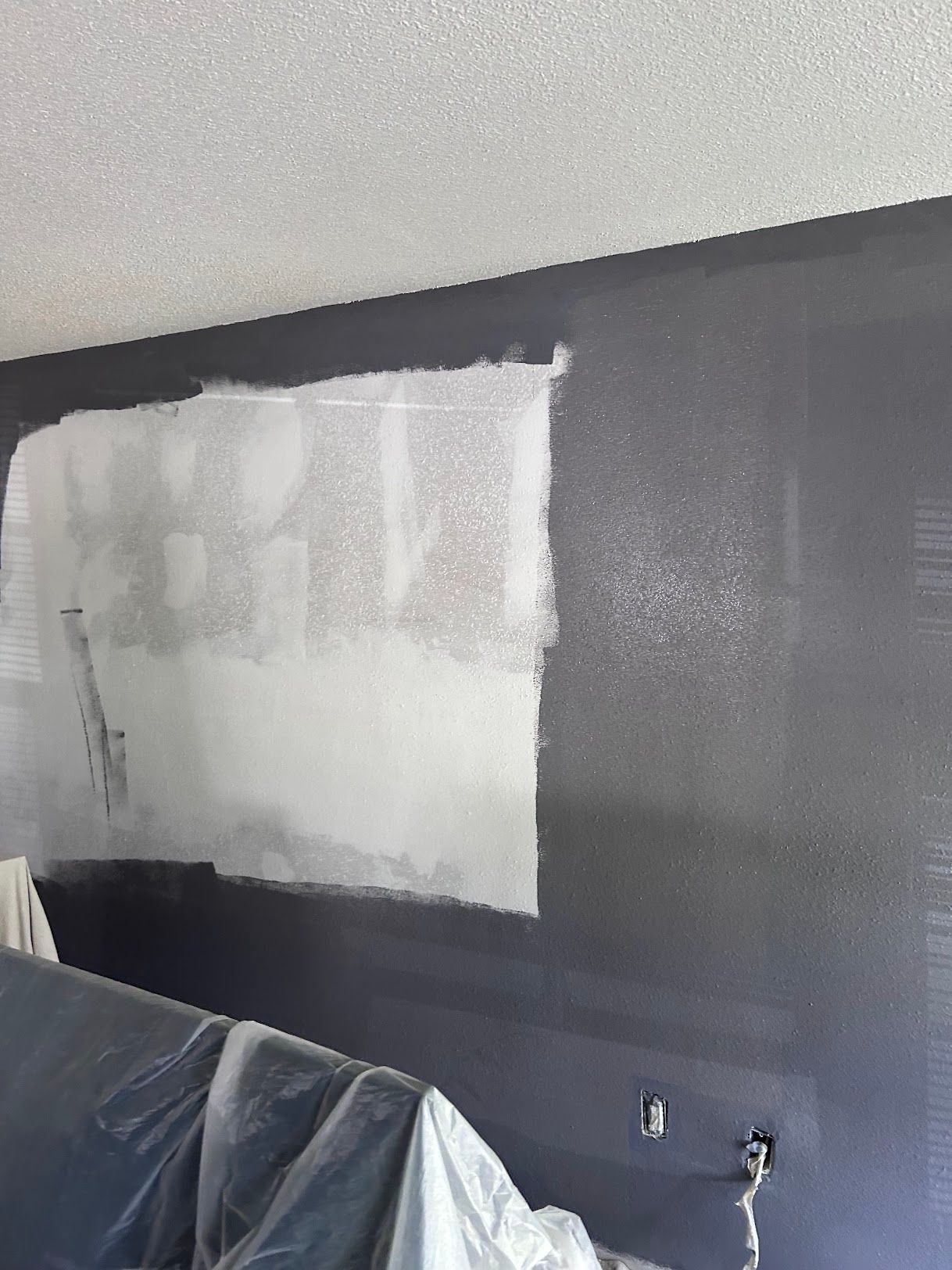 A wall is being painted in a room.