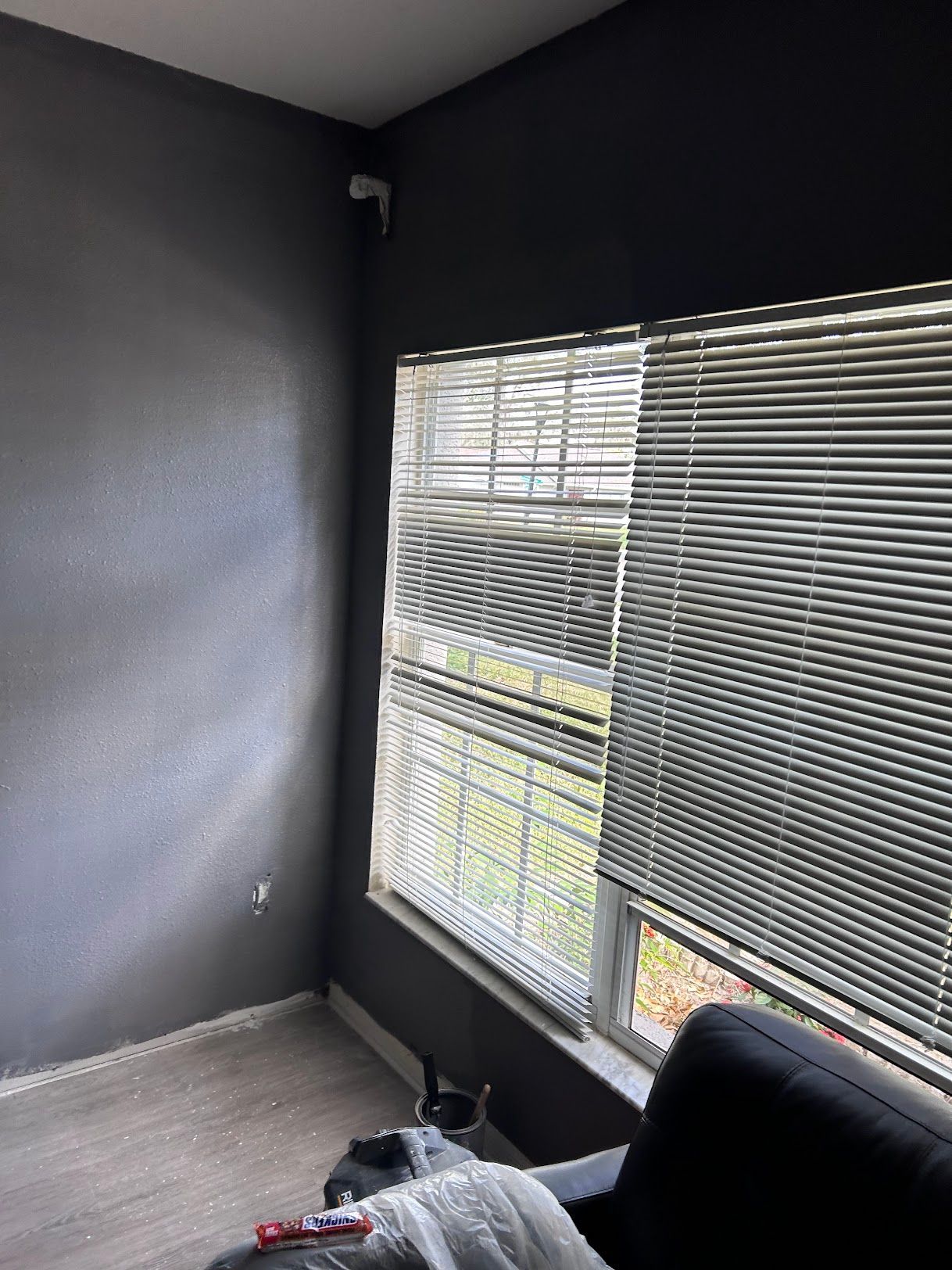 A living room with a couch and a window with blinds.