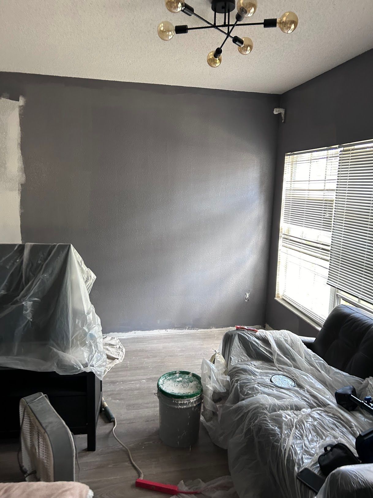 A living room with a couch and a chandelier being painted.