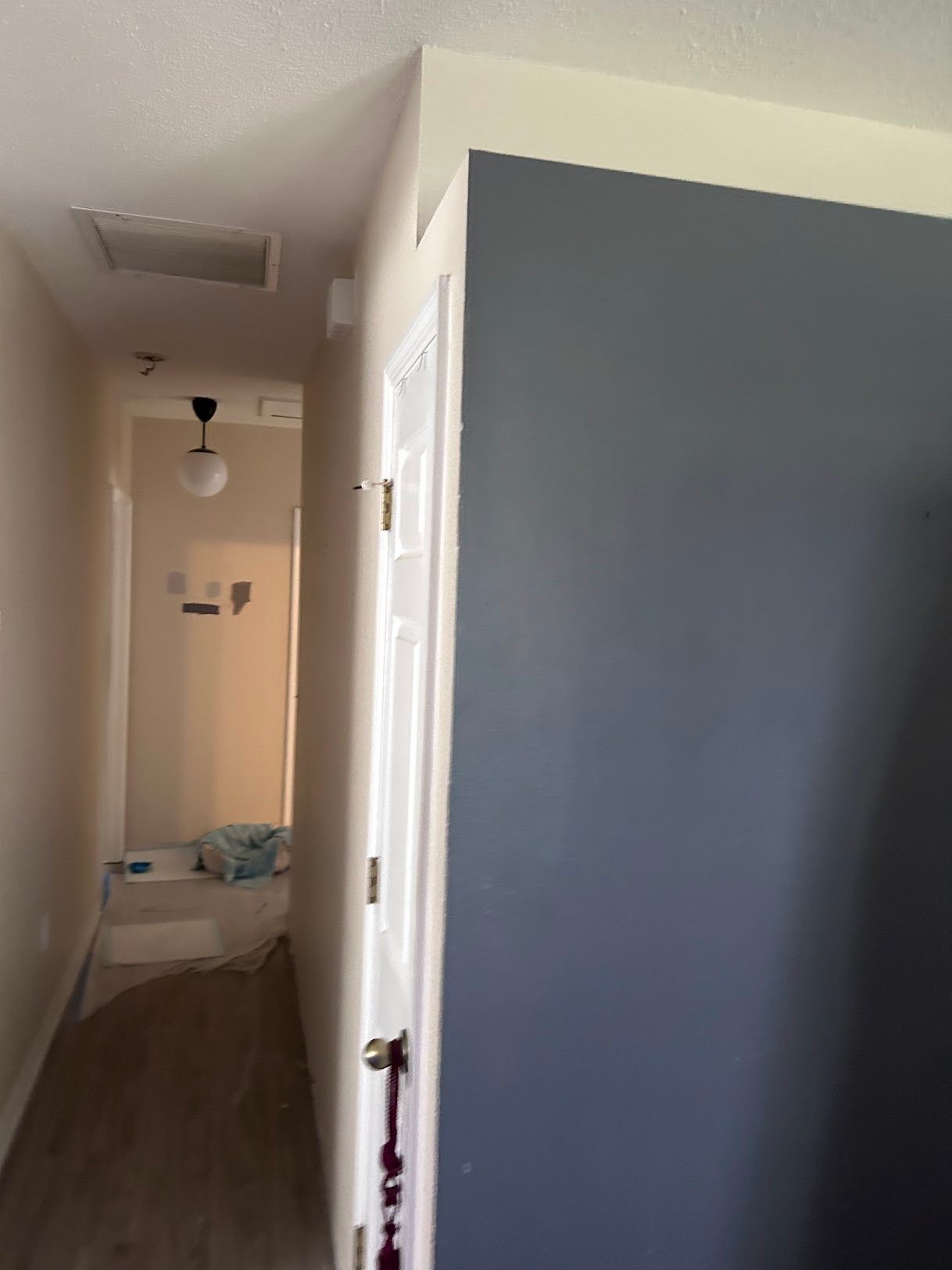 A hallway leading to a bathroom with a blue wall