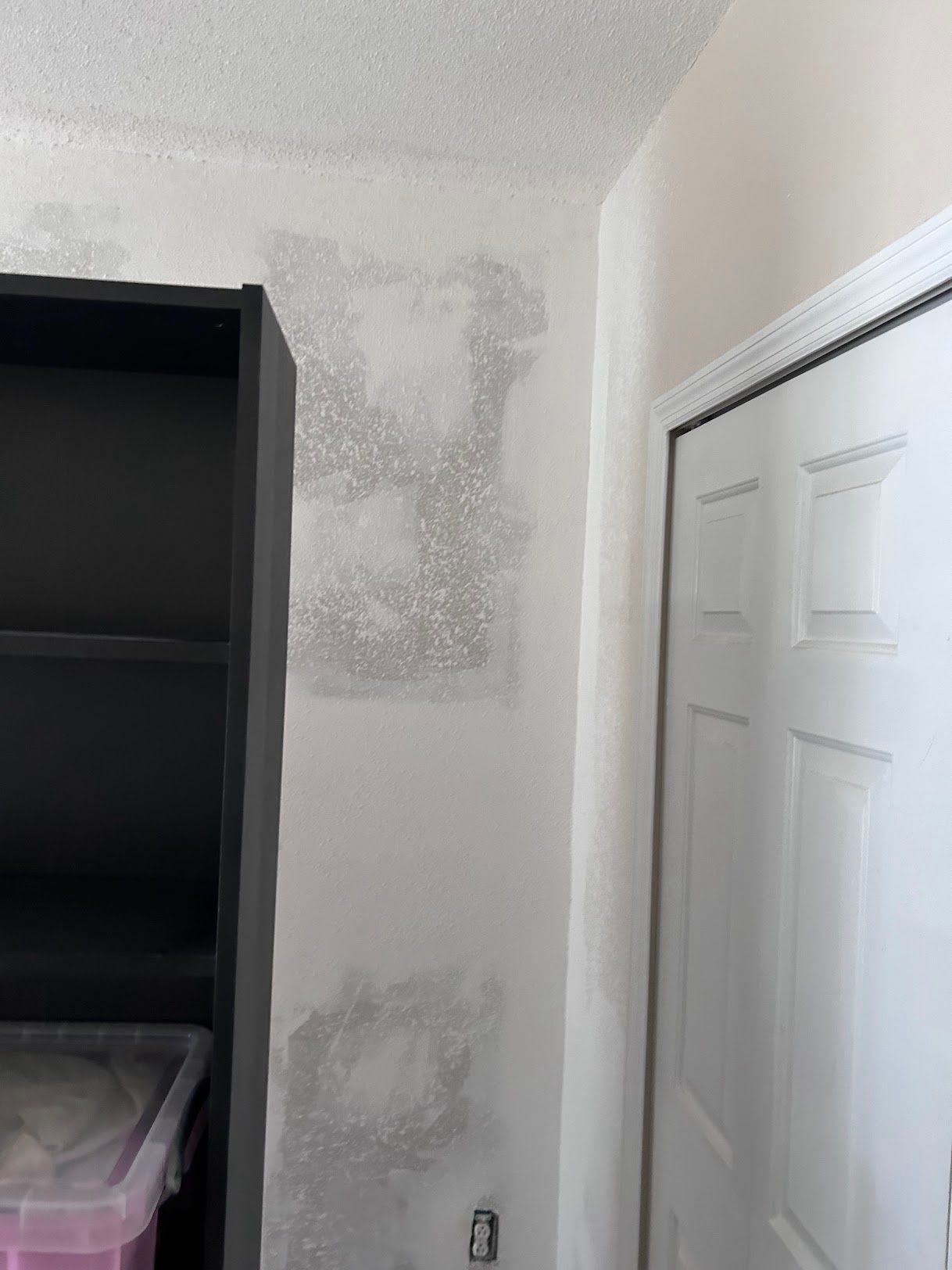 A room with a closet and a bookshelf and a white door.