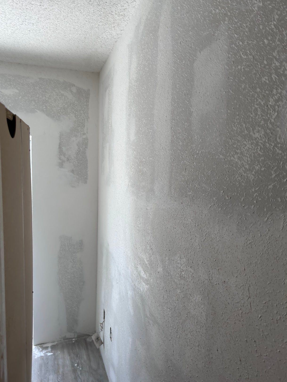 A corner of a room with a white wall and a door.