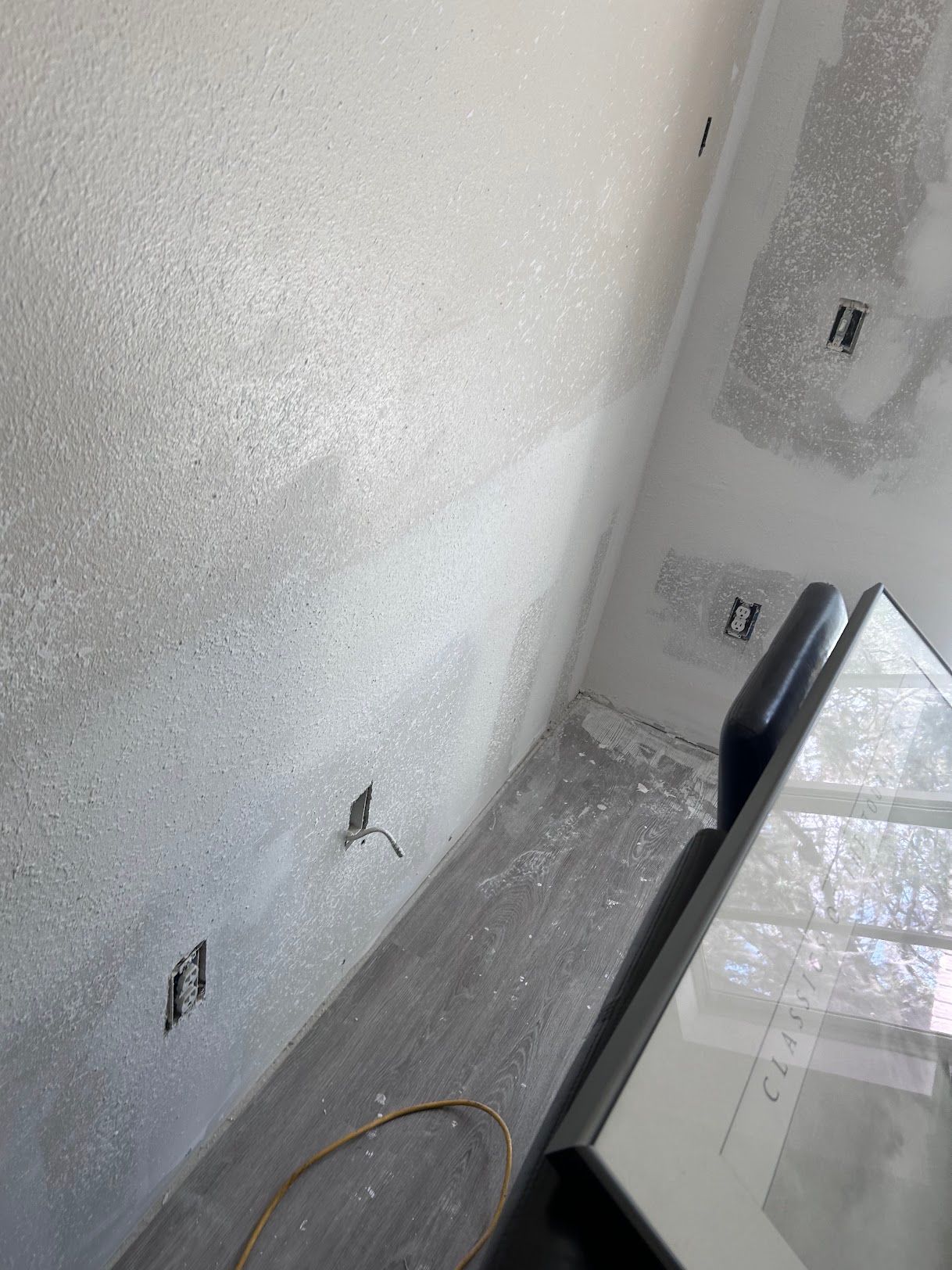 A room with a white wall and a picture frame on the floor.