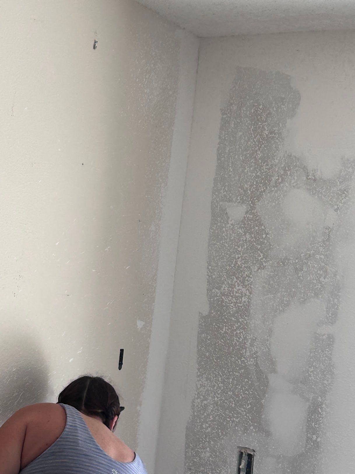 A woman is working on a wall in a room.