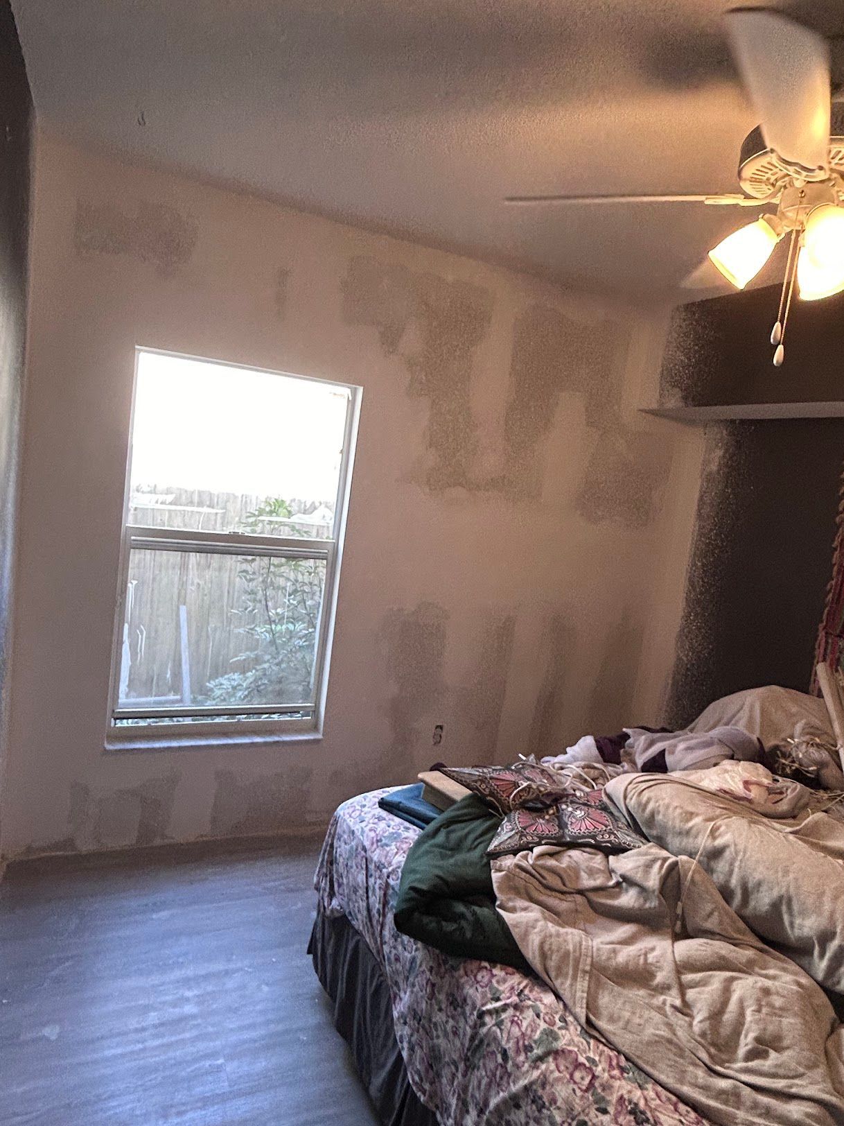 A bedroom with a bed , ceiling fan , and window.