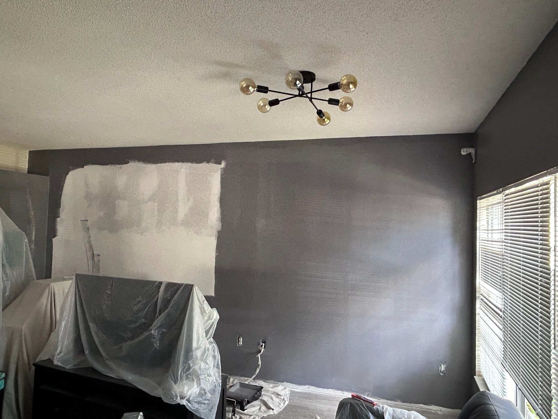 A living room with gray walls and a chandelier hanging from the ceiling.