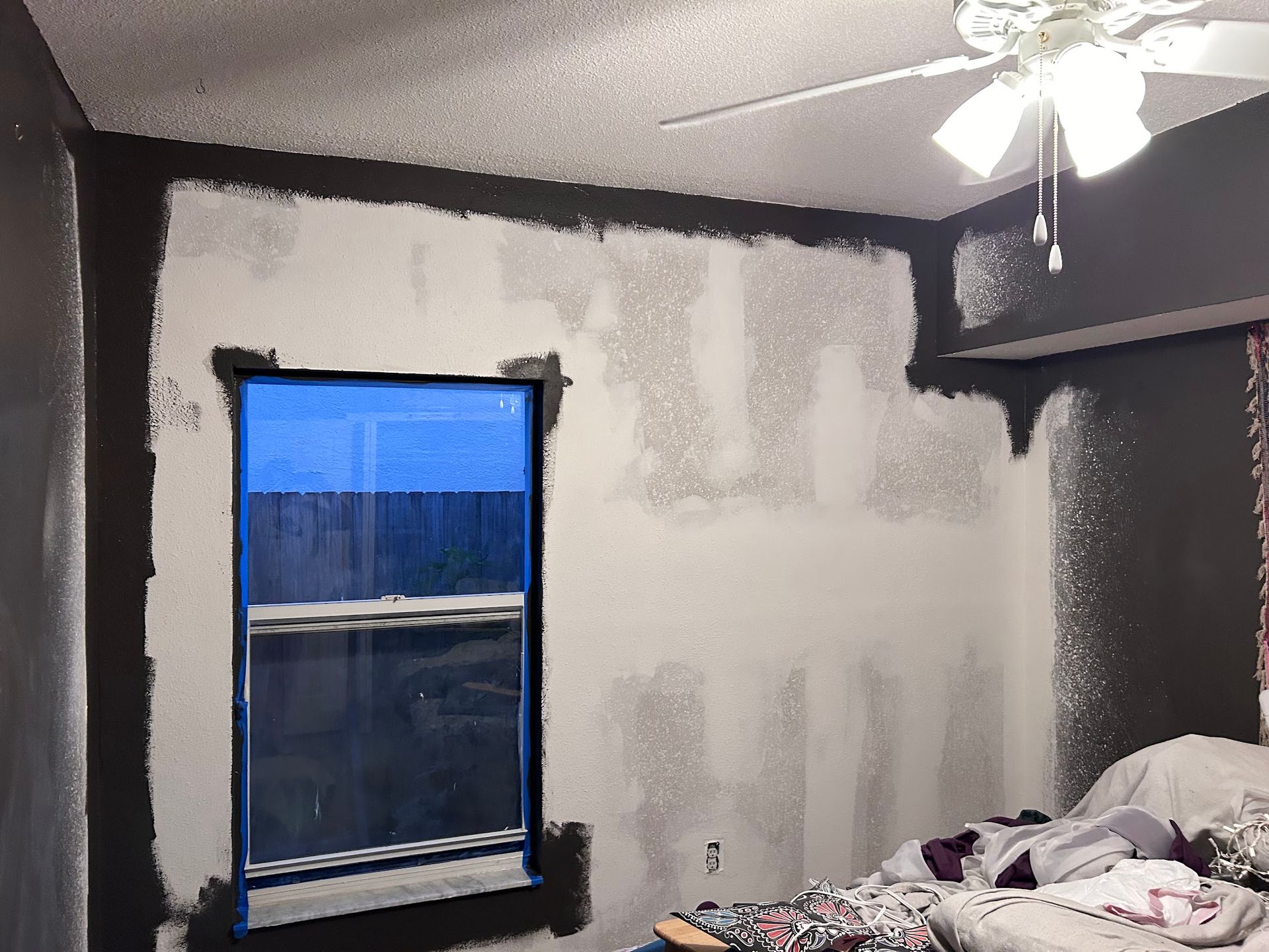 A bedroom with a ceiling fan and a window