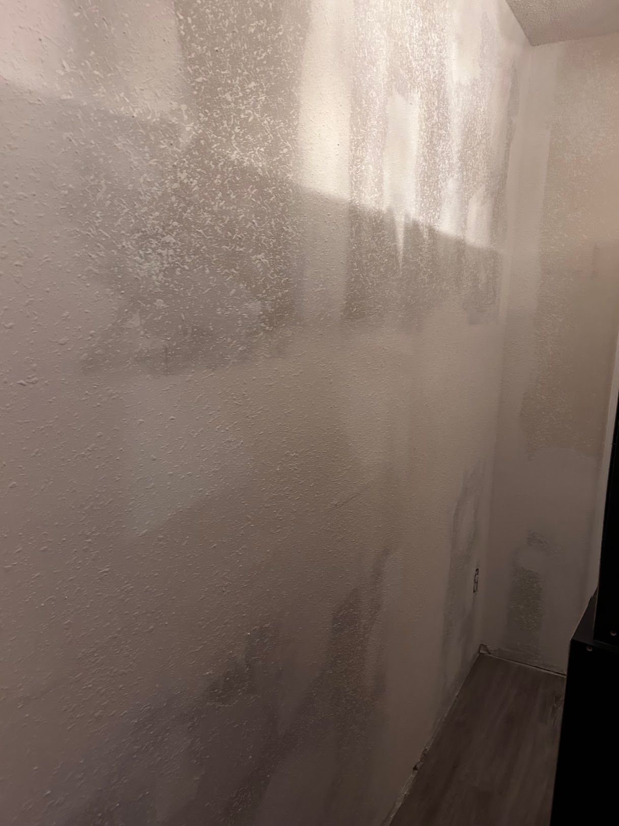 A room with a white wall and a wooden floor.