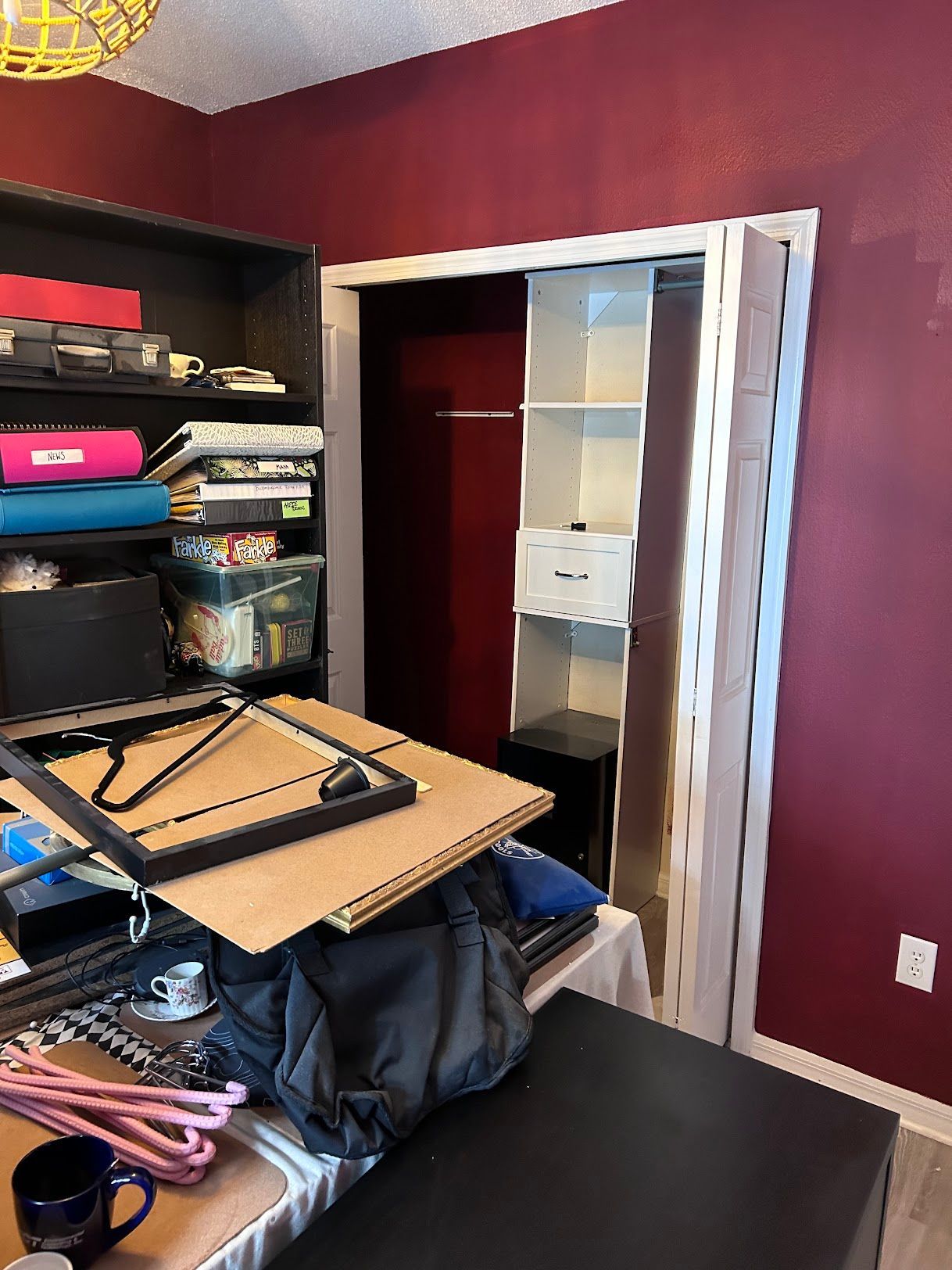 A room with red walls and a closet filled with lots of items.