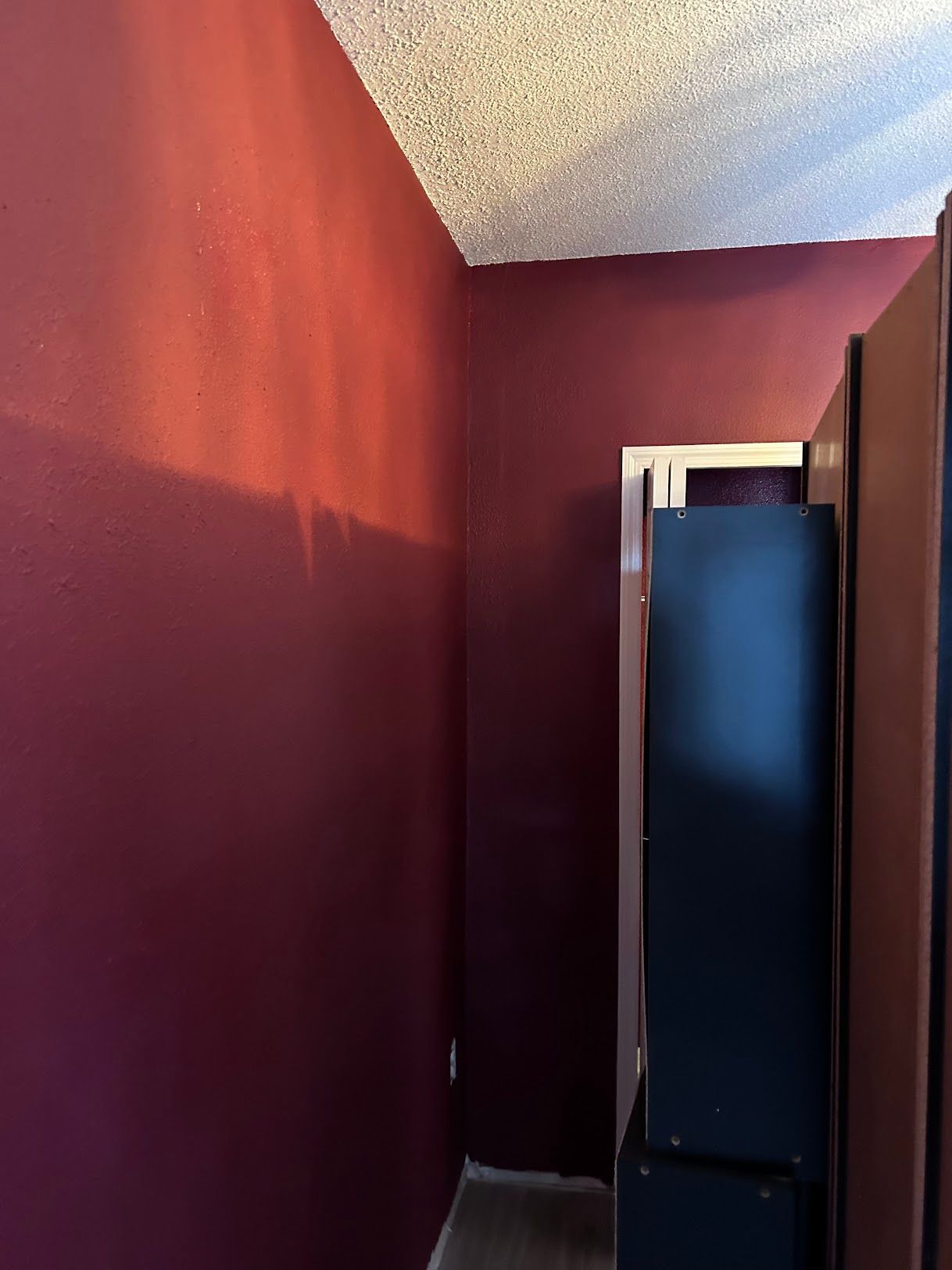 A room with red walls and a black refrigerator.