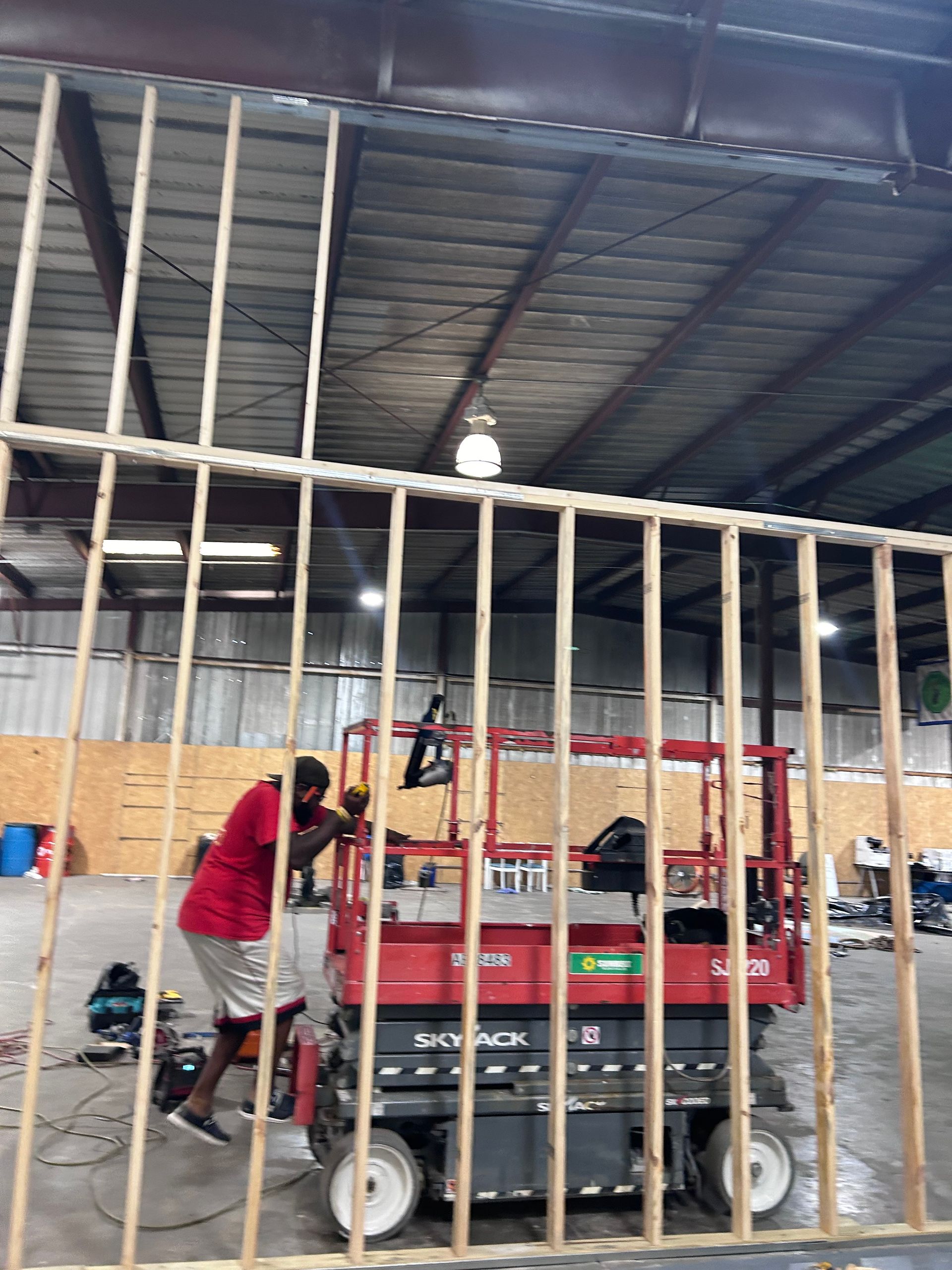 A man is working on a scissor lift in a warehouse.