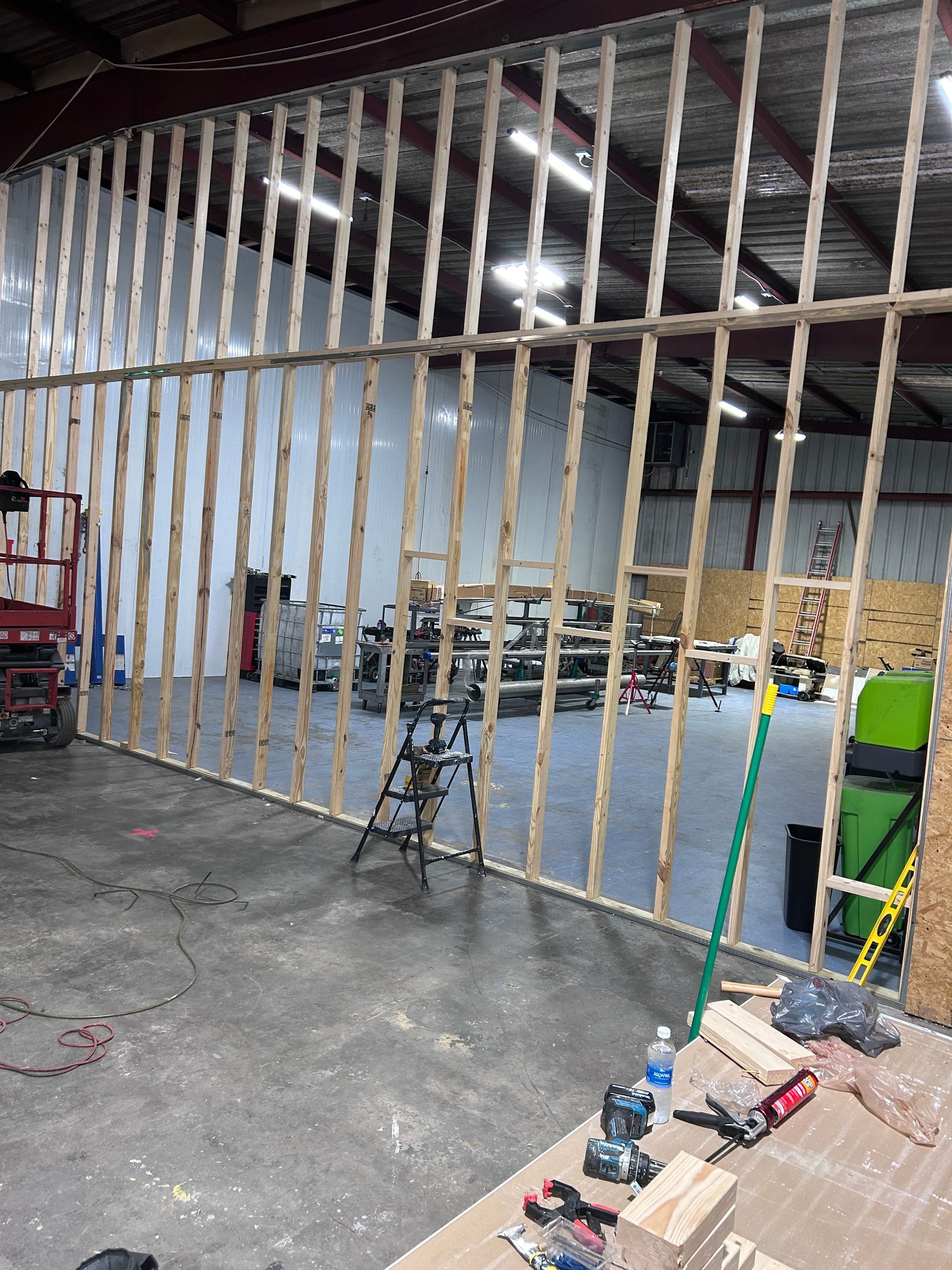 A large wooden wall is being built in a warehouse.