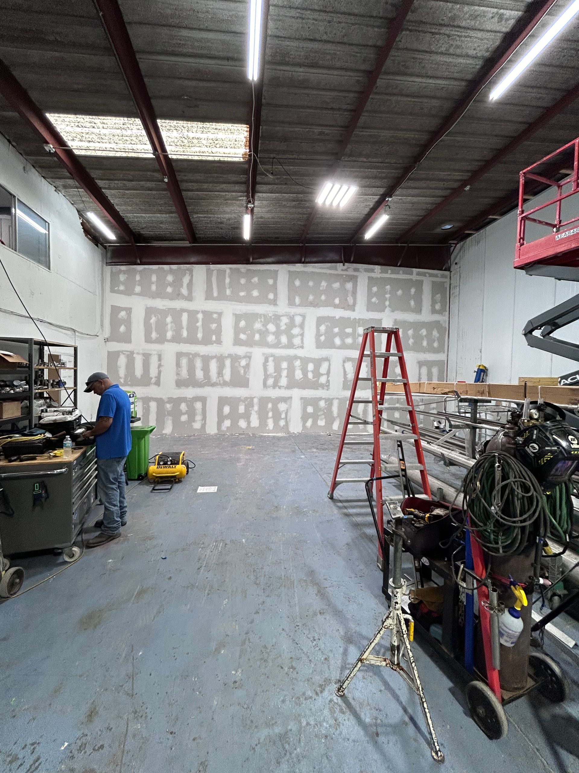 A man is working in a warehouse with a ladder.