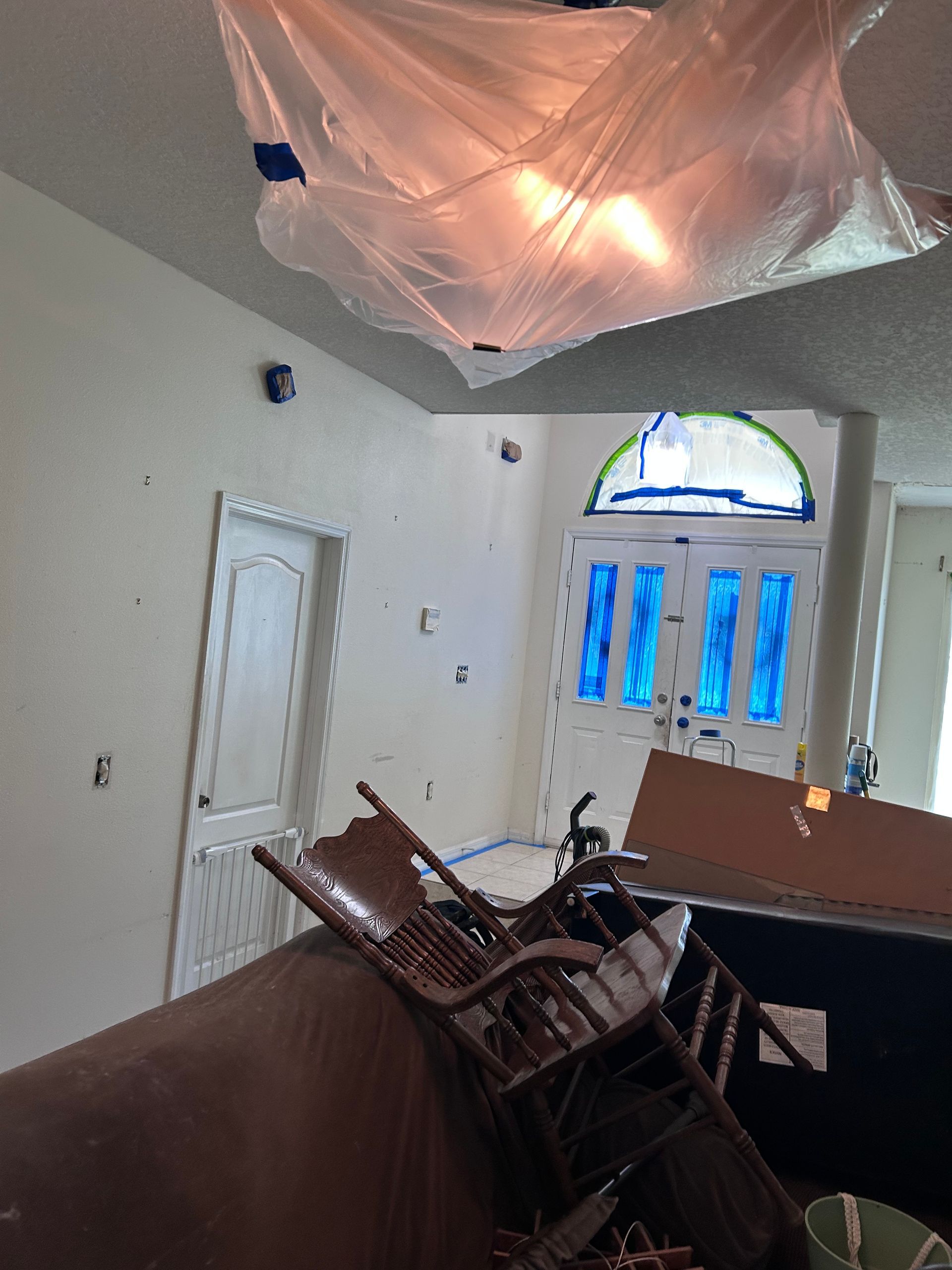 A living room with a ceiling that is covered in plastic.