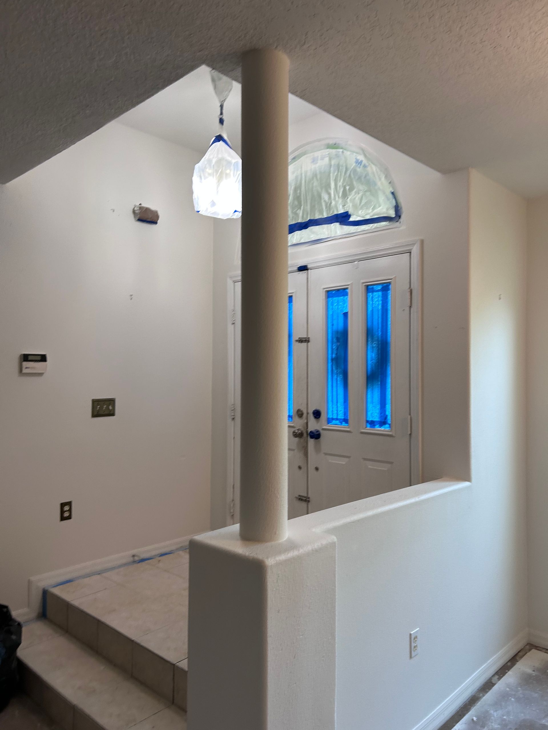 An empty room with a blue door and a pillar