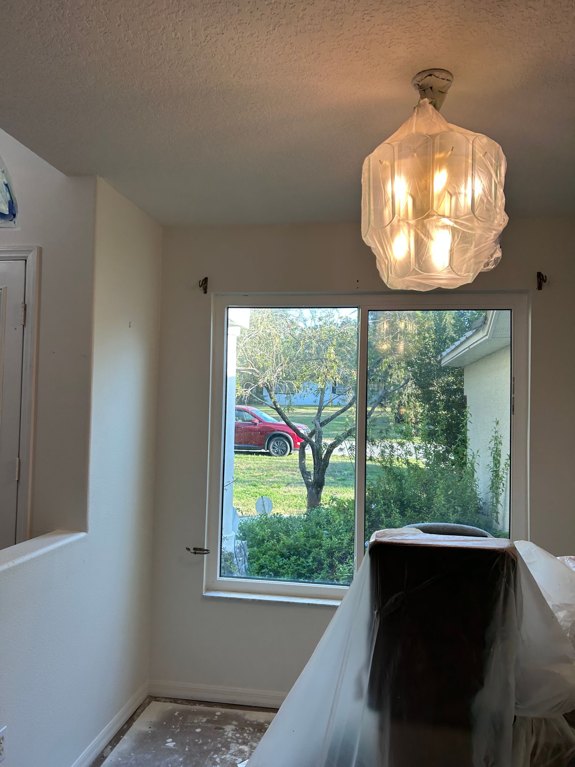A room with a window and a chandelier hanging from the ceiling.
