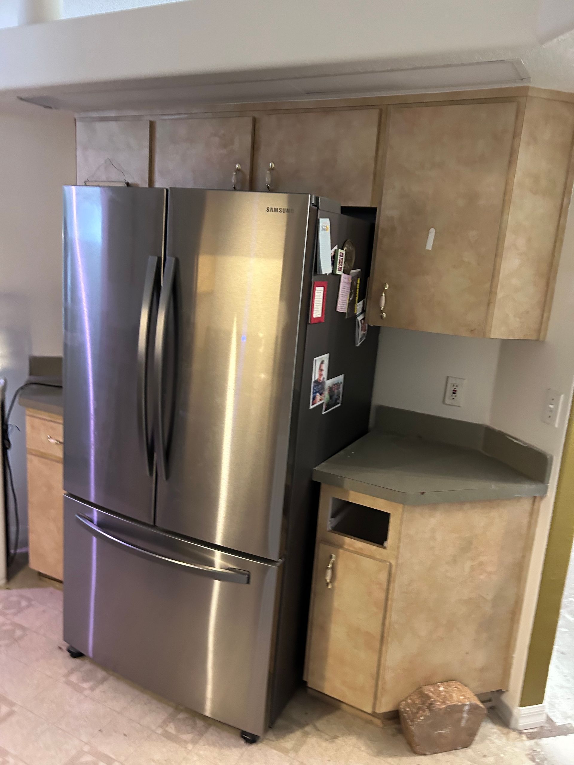 A stainless steel refrigerator is sitting in a kitchen next to a counter.