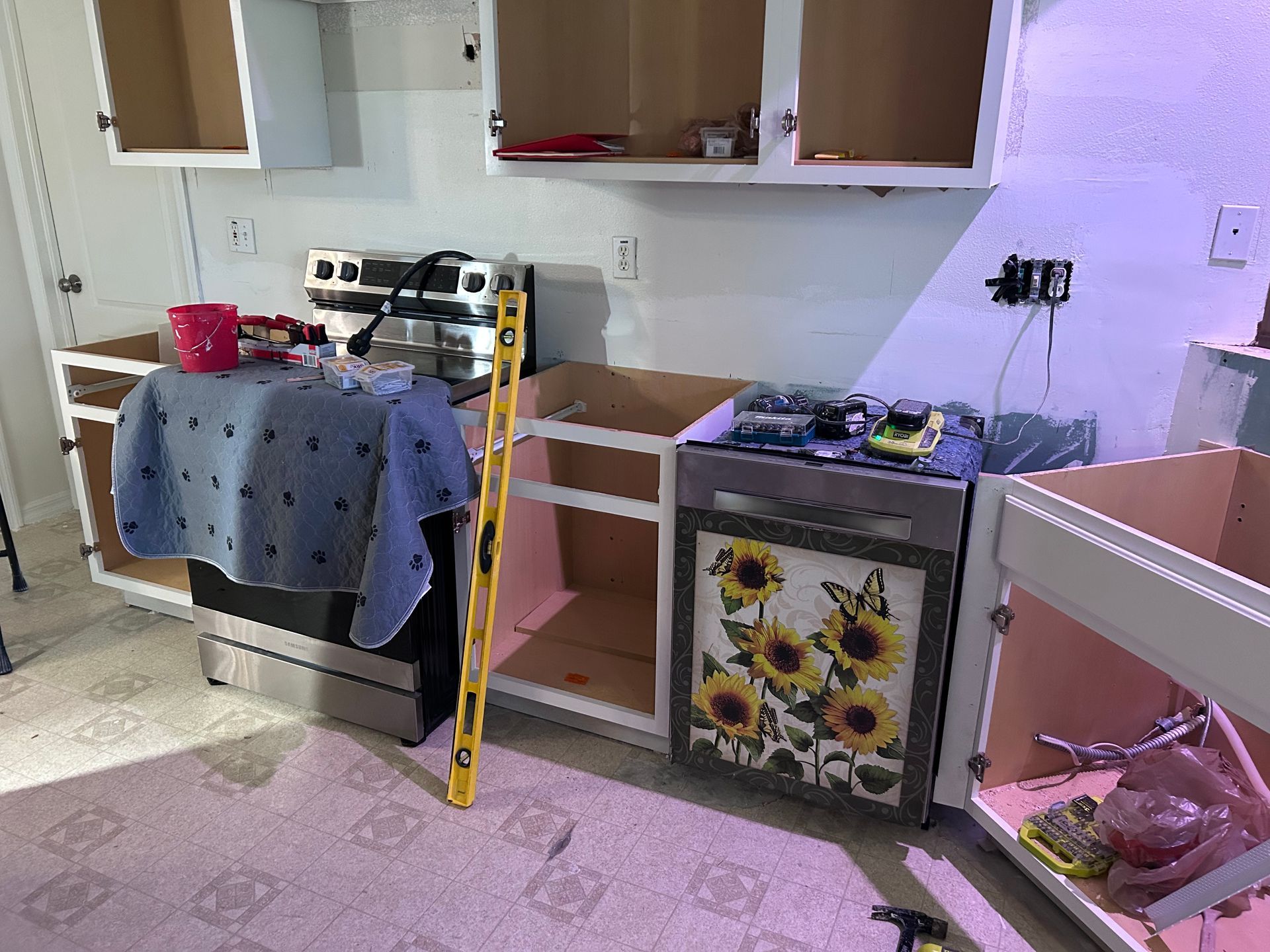 A kitchen with a stove , dishwasher , and cabinets being built.