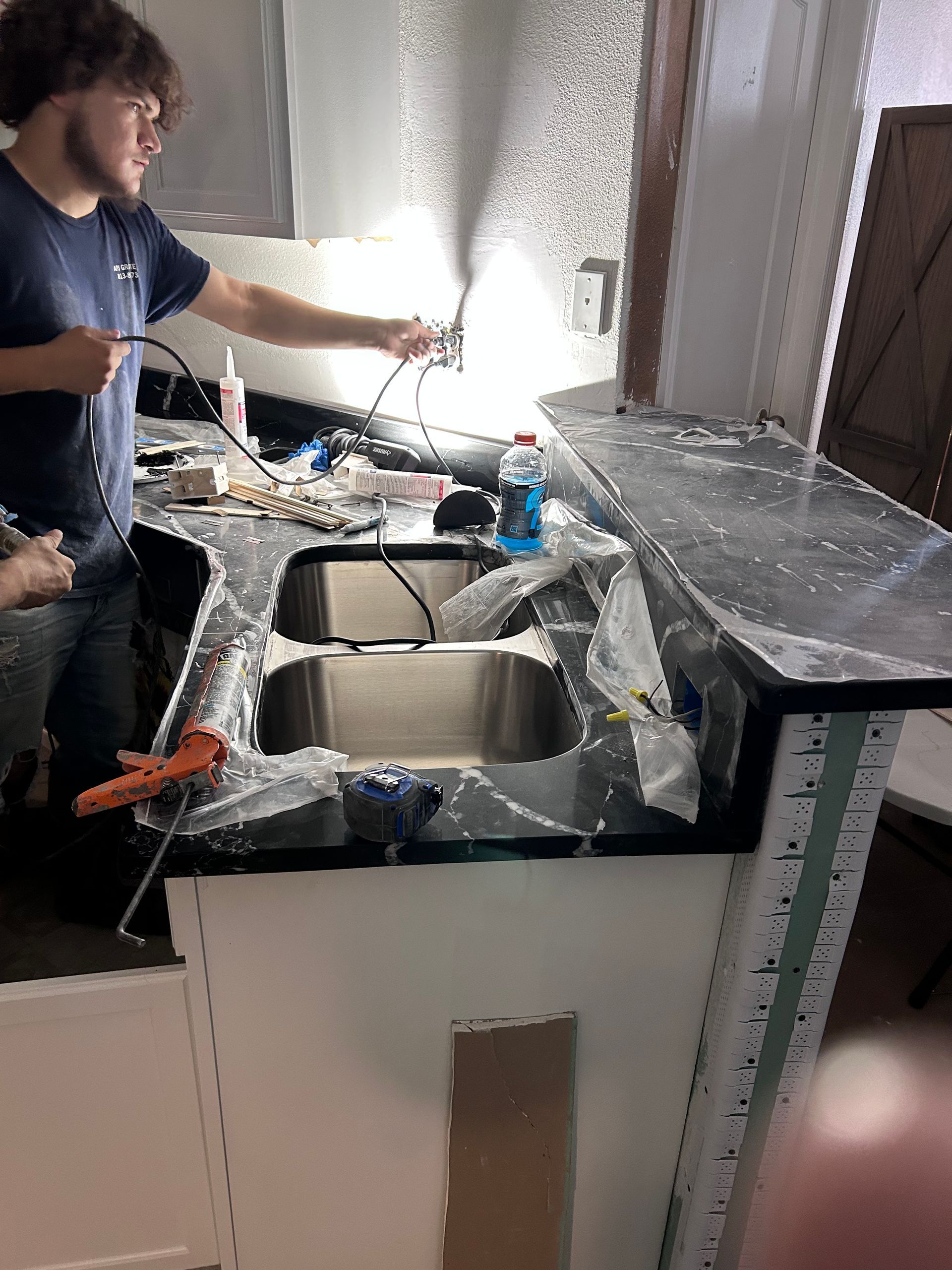 A man is working on a kitchen counter with a sink.