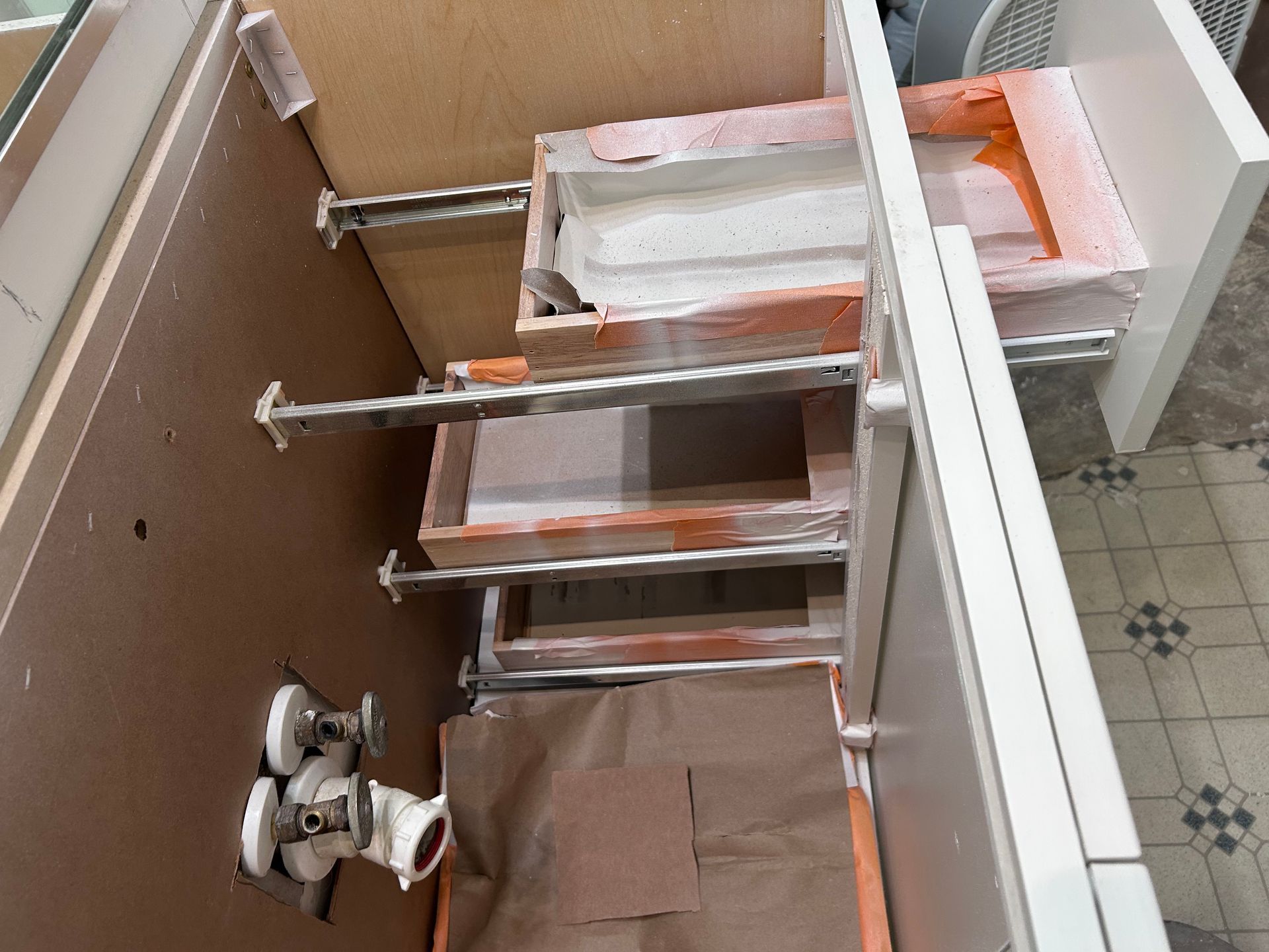 The inside of a cabinet with drawers and a faucet