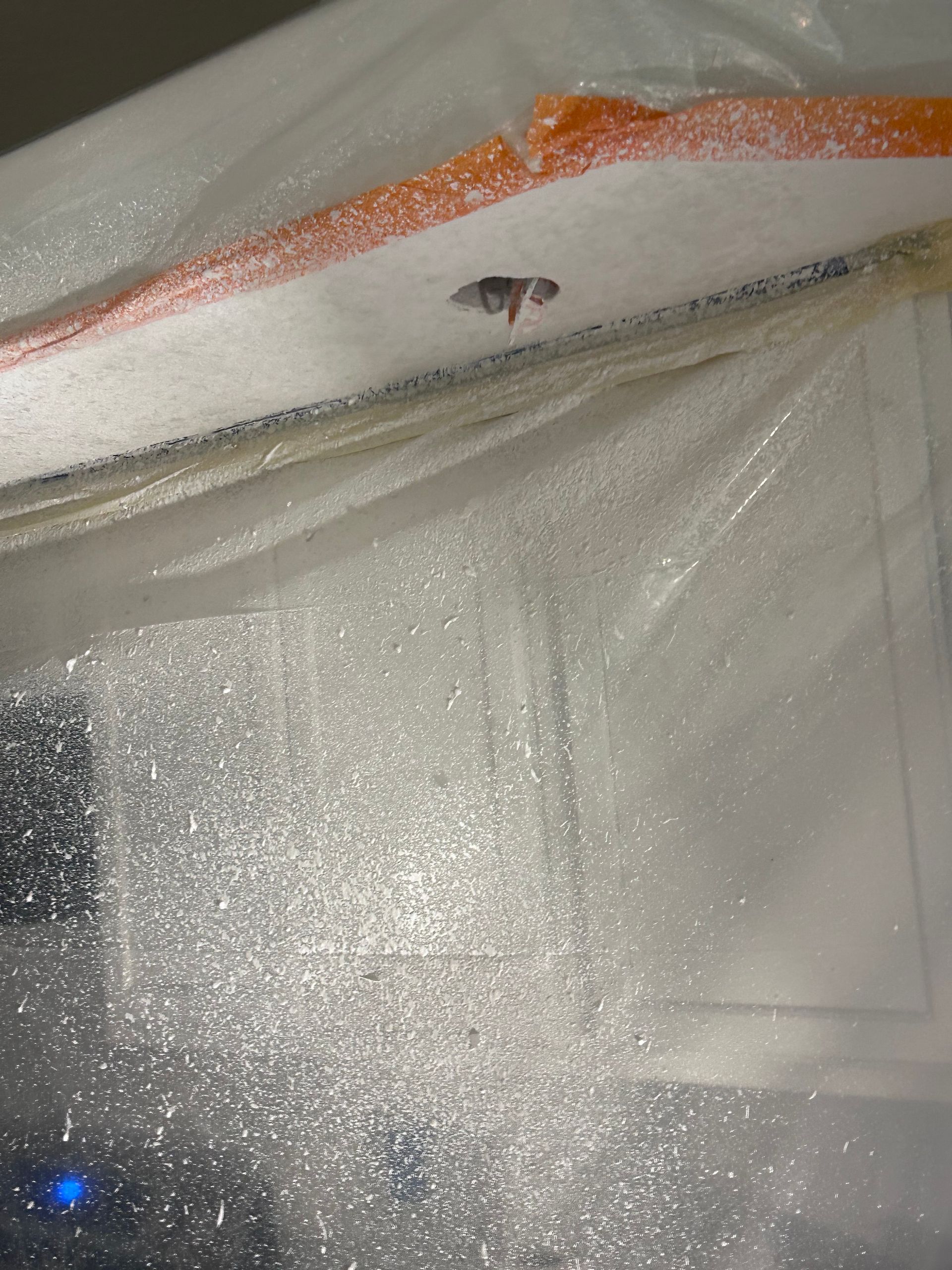 A ceiling with a hole in it is covered in plastic.