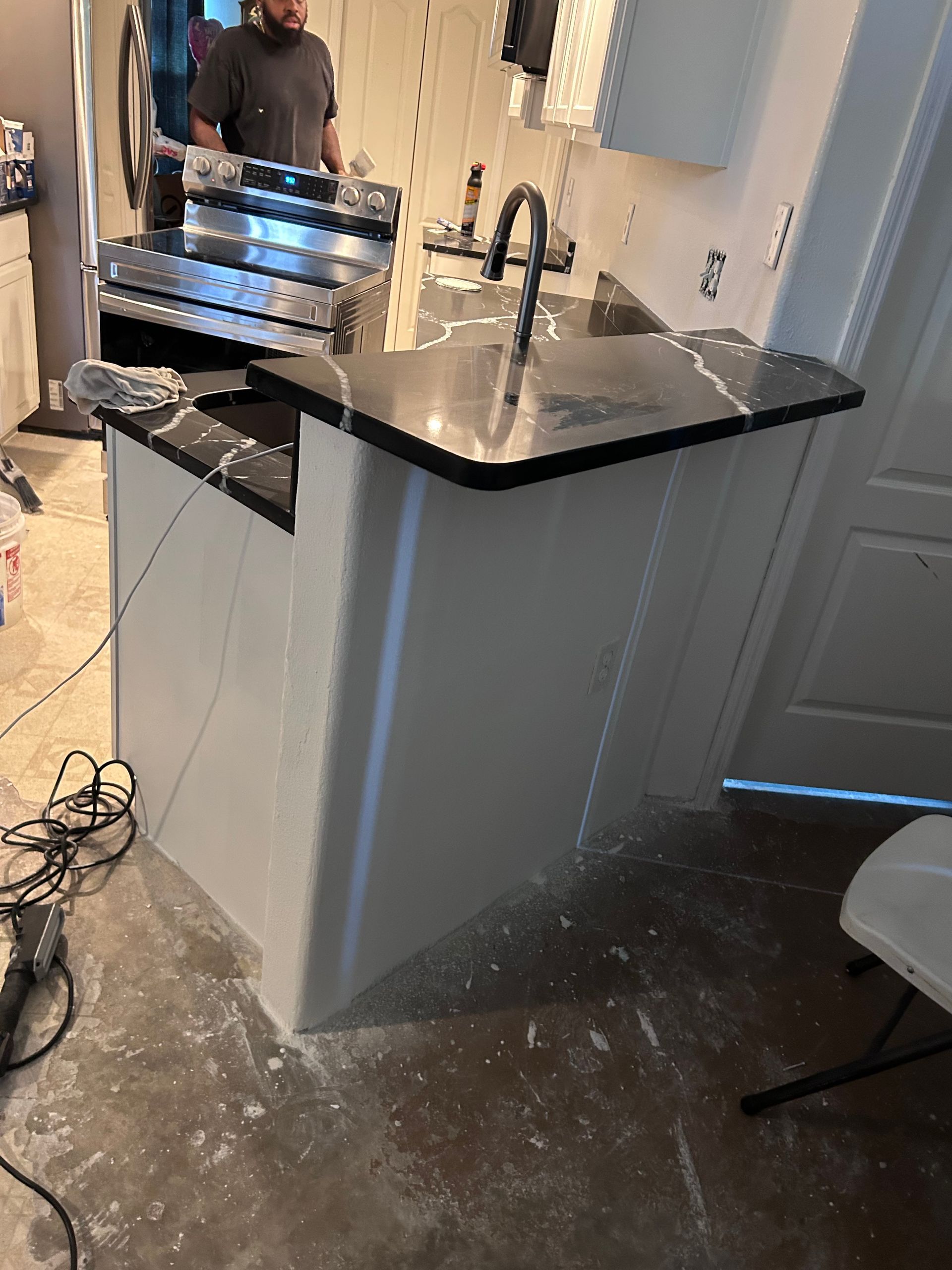 A man is standing in a kitchen next to a sink.