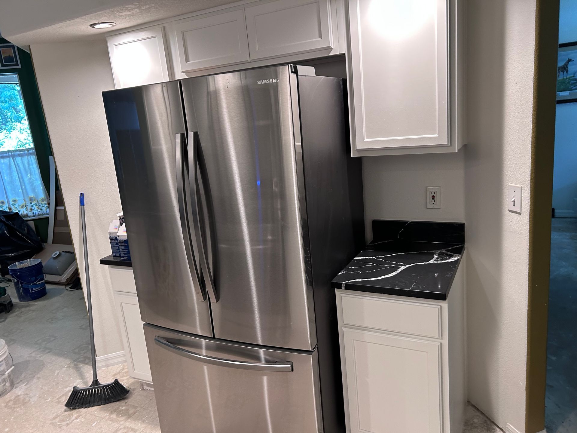 A stainless steel refrigerator is sitting in a kitchen next to a counter.