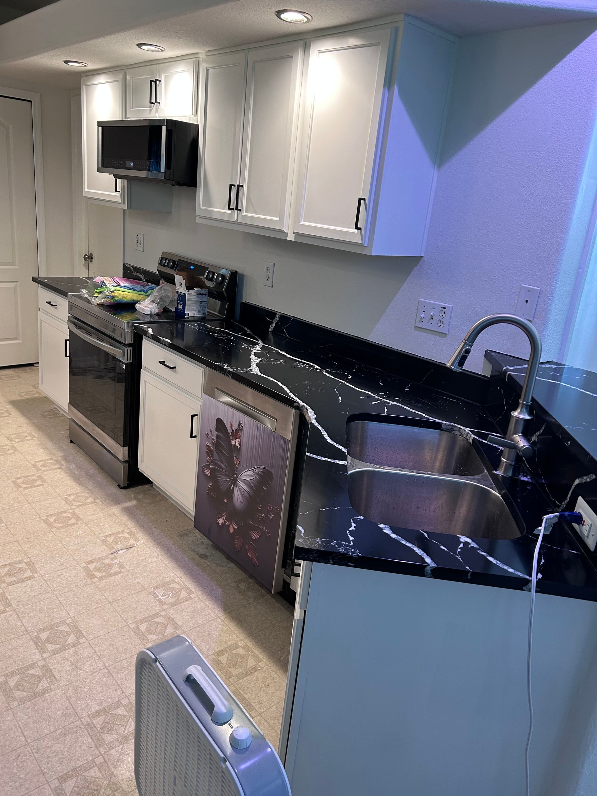 A kitchen with black counter tops and white cabinets