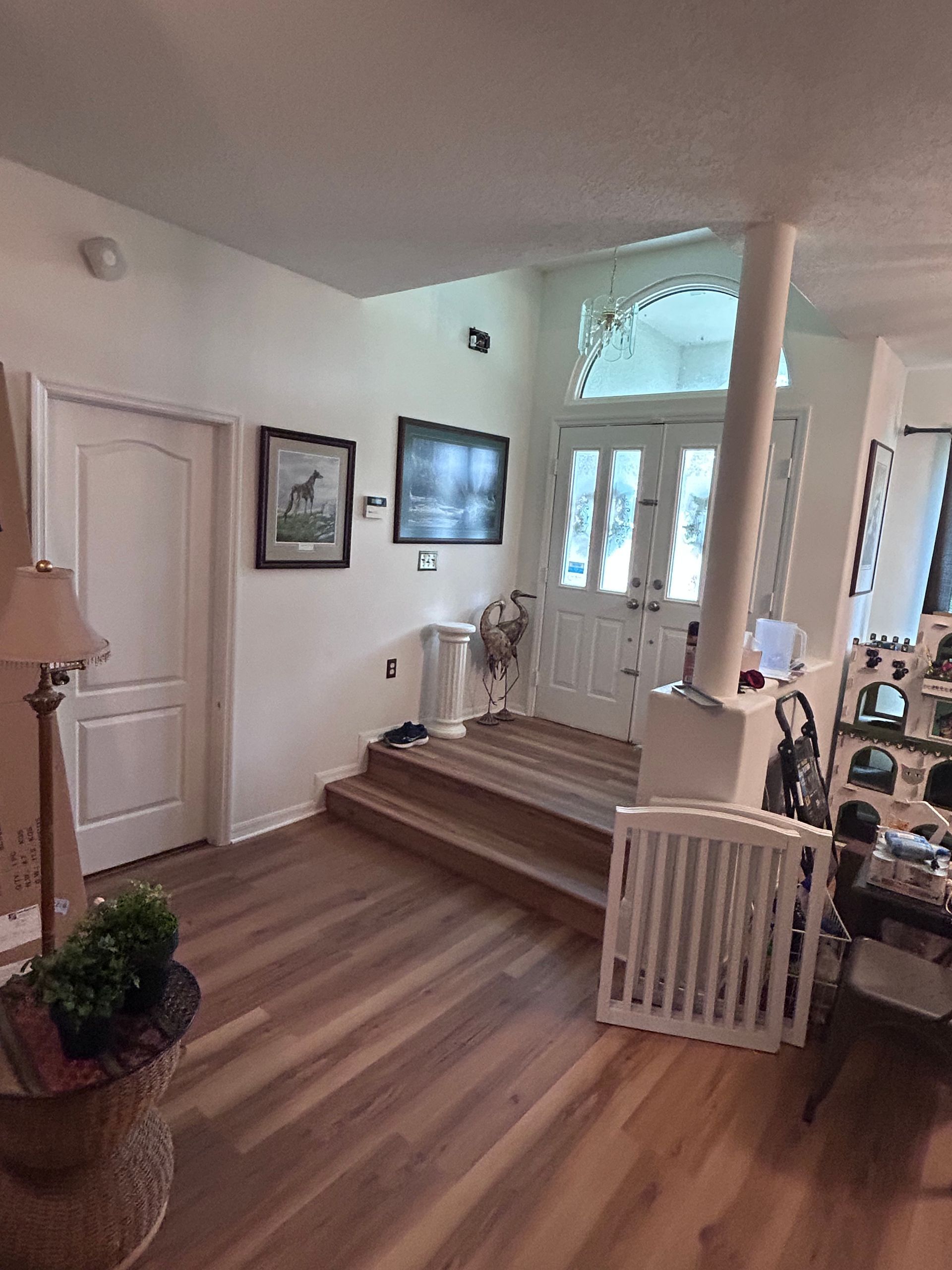 A living room with hardwood floors and a staircase leading to the front door.
