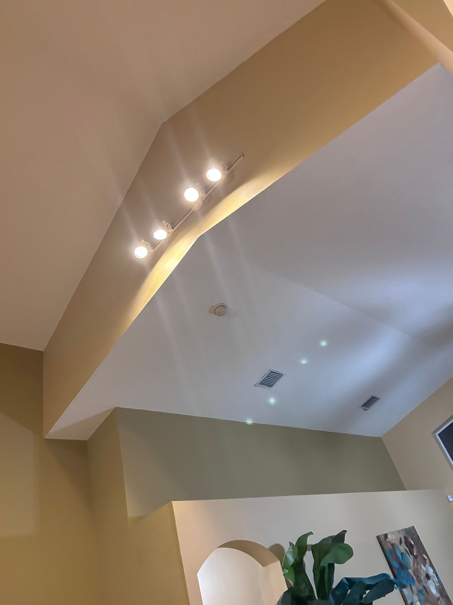 Beige and white angled ceiling with recessed lights and track lighting.