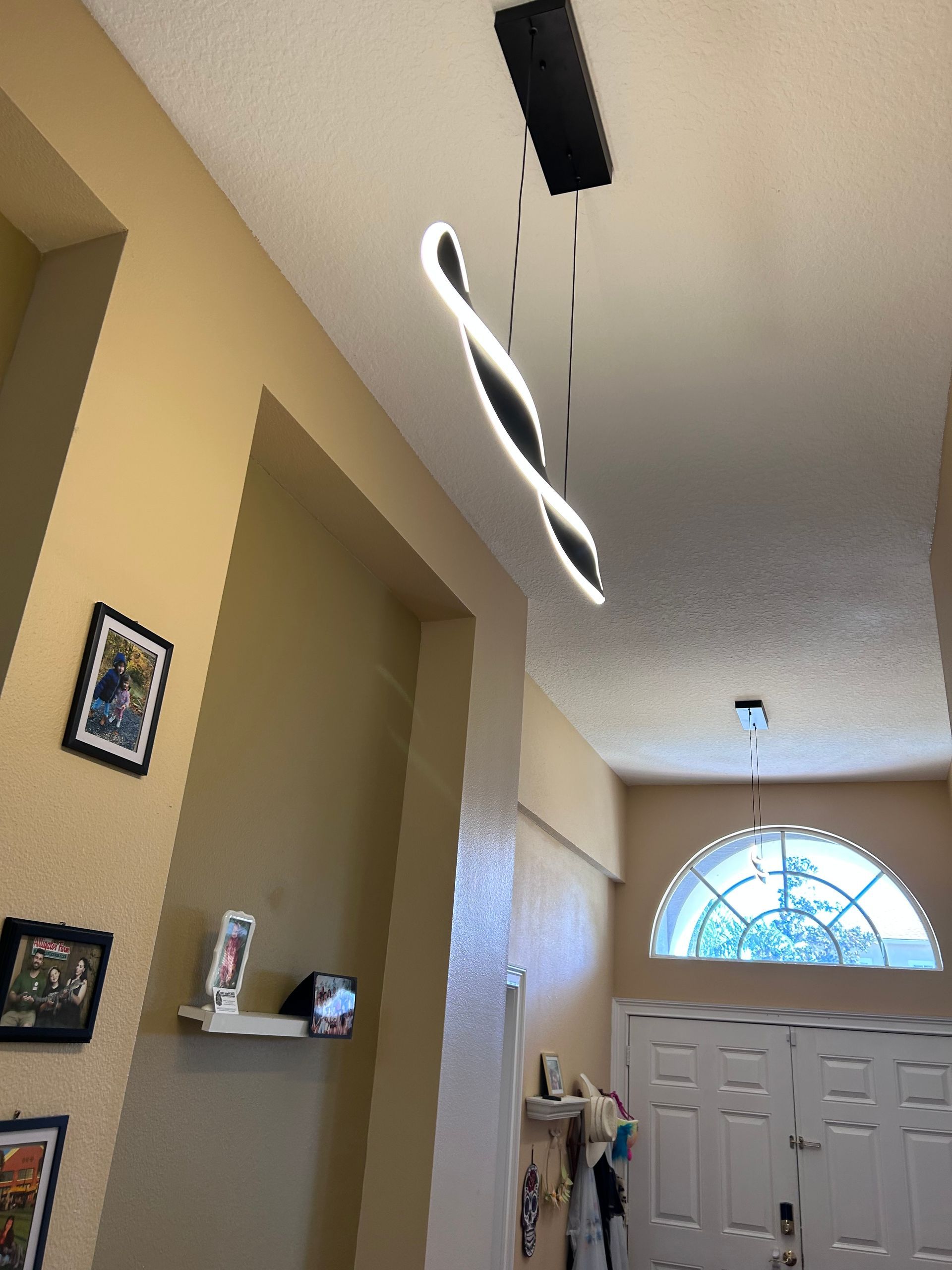 Modern pendant light fixture in hallway with beige walls and a white door.