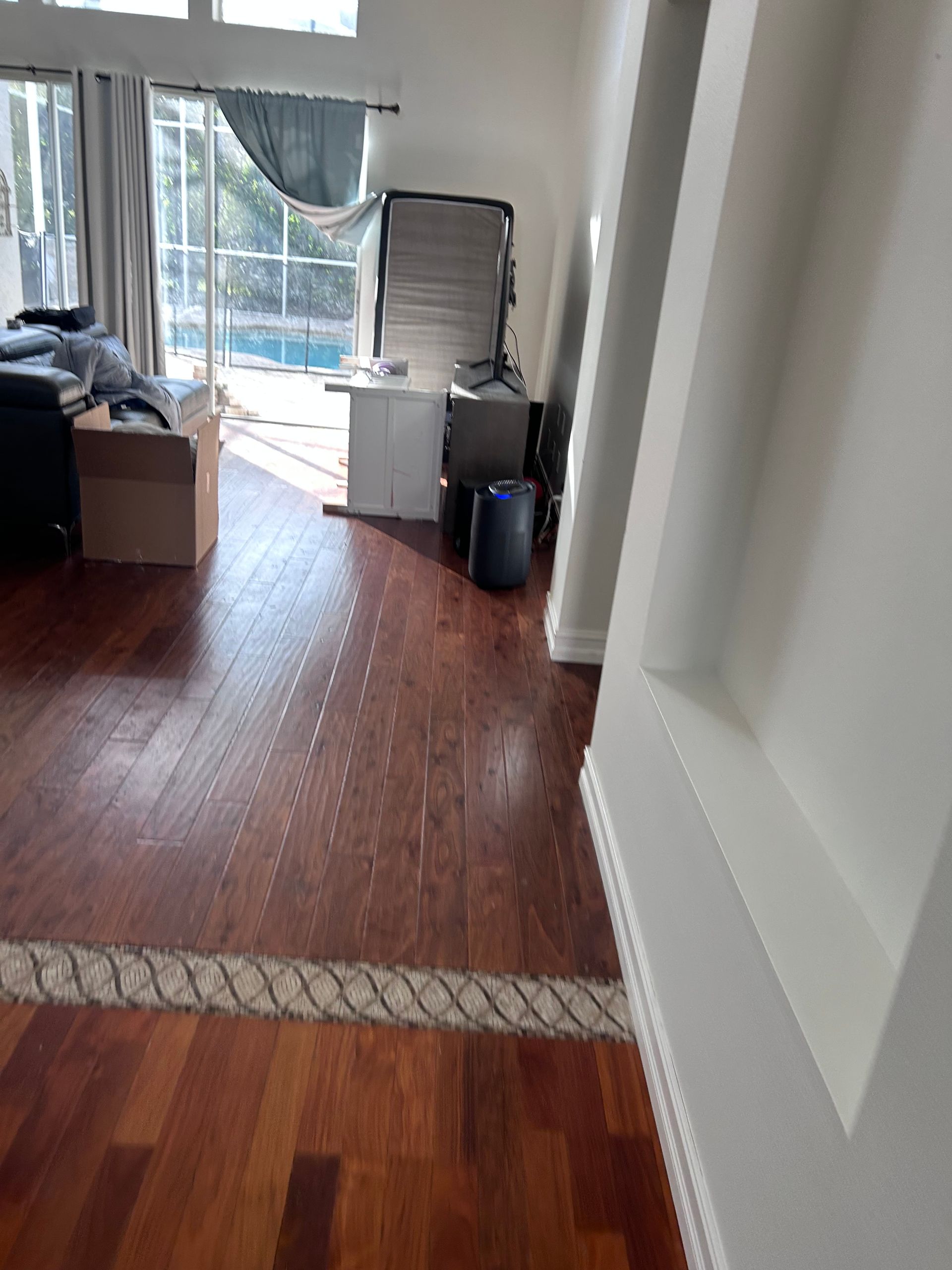 Hardwood floor interior with boxes, furniture, and a sliding glass door to a pool.