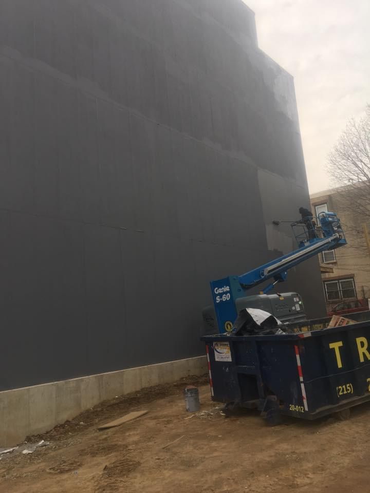 A blue dumpster is parked in front of a large building.