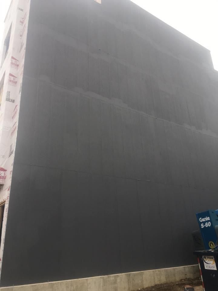 A large building with a gray wall is being built.