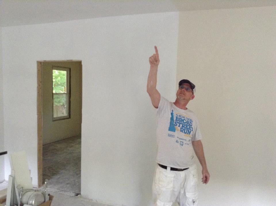 A man in a white shirt is pointing up in a room.