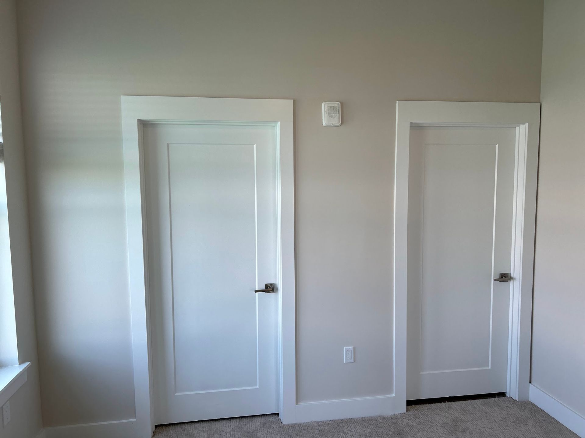 A bedroom with two white doors and a window.