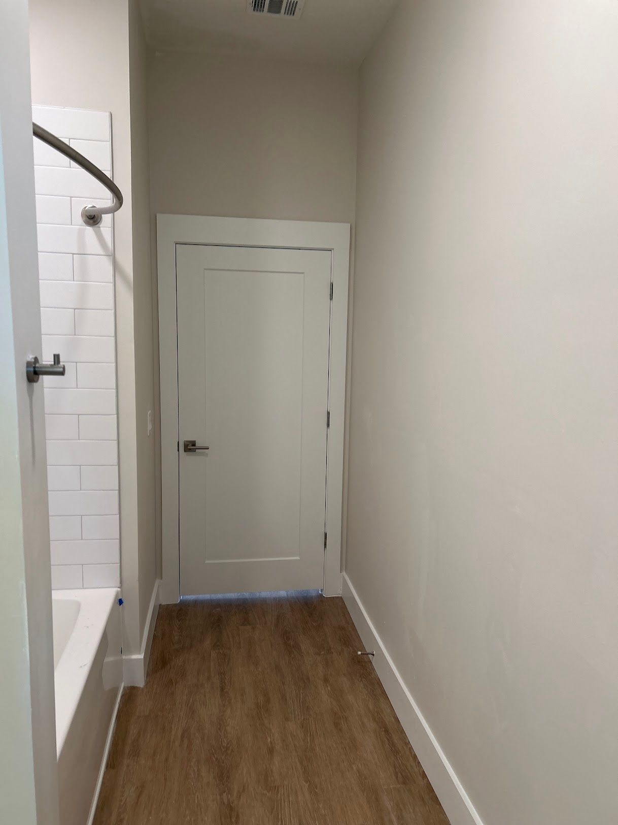 A hallway in a bathroom with a bathtub and shower.