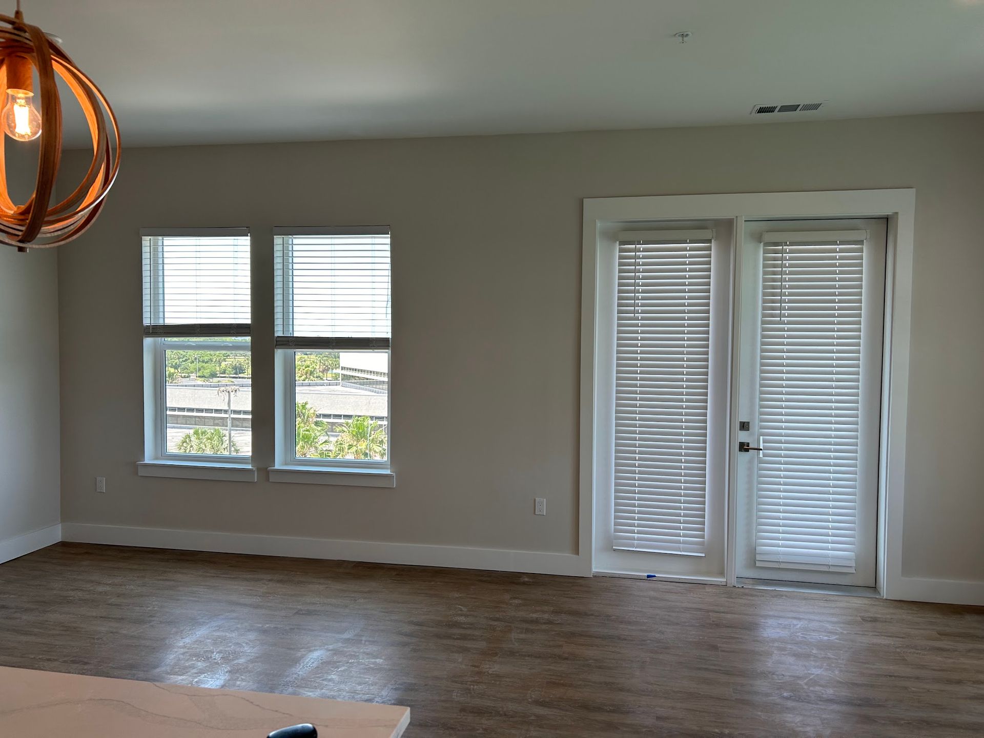 An empty living room with two windows and a door