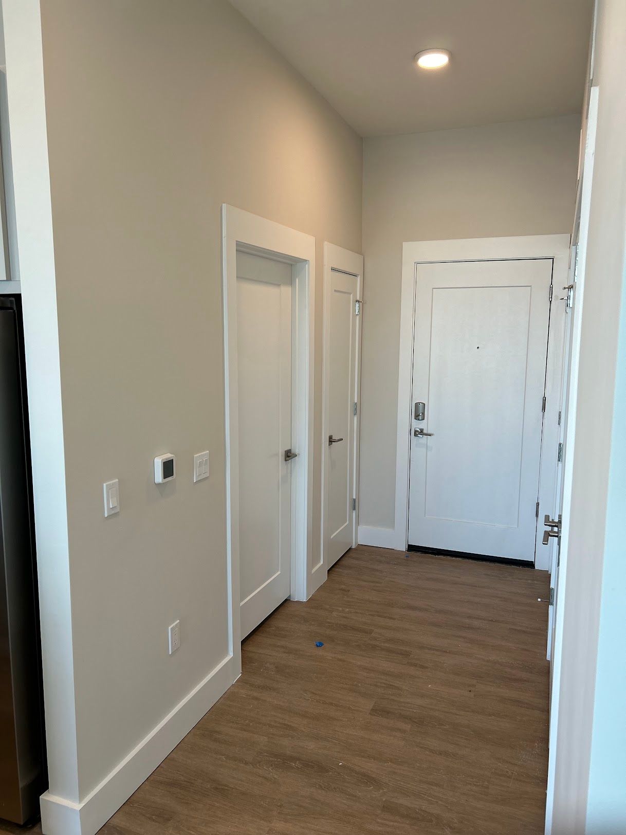 A white shed with two doors and two windows on a brick patio.