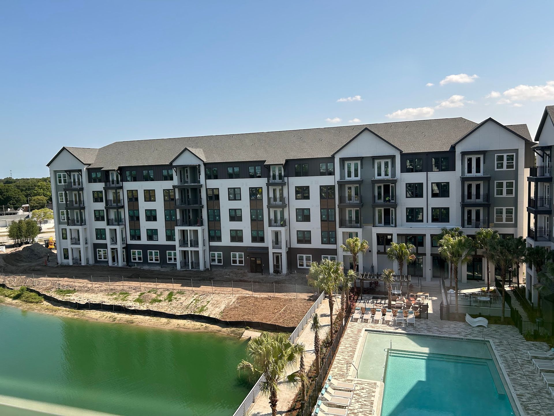A large apartment building with a swimming pool in front of it.