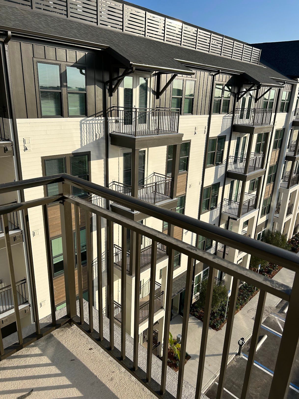 A balcony overlooking a large apartment building with a metal railing.