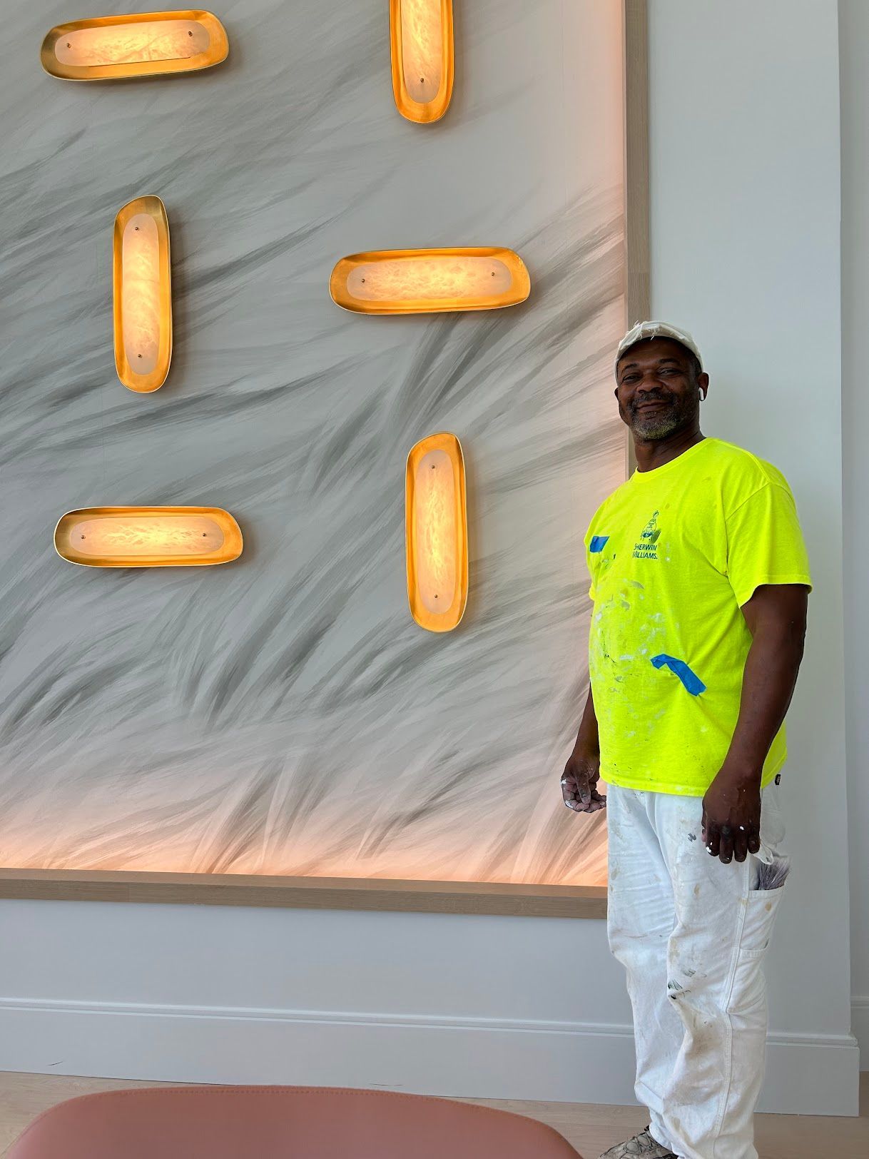 A man in a neon yellow shirt is standing in front of a wall with lights on it.